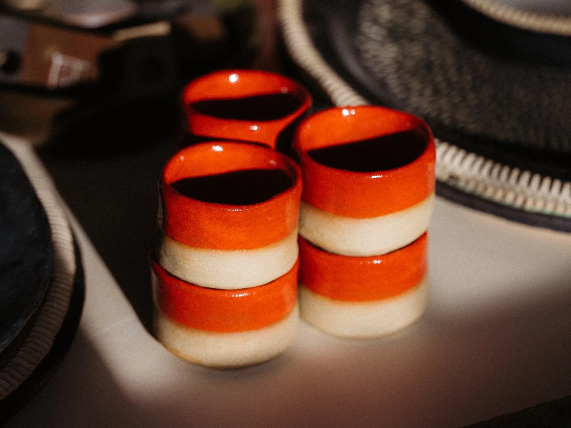 Close-up of four small stacked ceramic espresso cups with a red and beige striped design on a table.