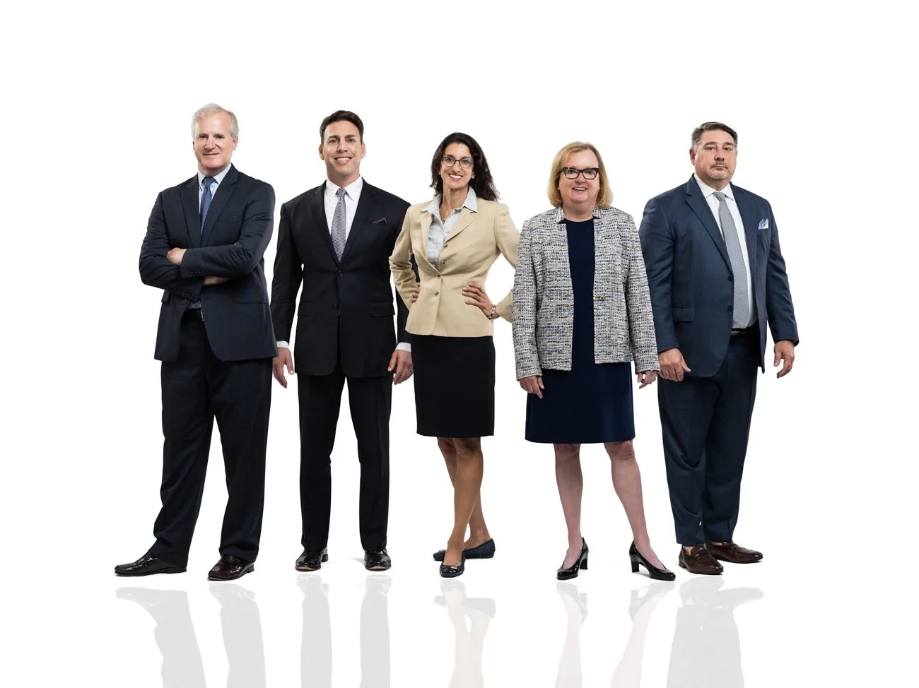 Group of five professionally dressed people standing against a white background.