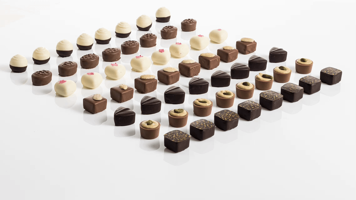 Assorted chocolates arranged in a pattern on a white background.