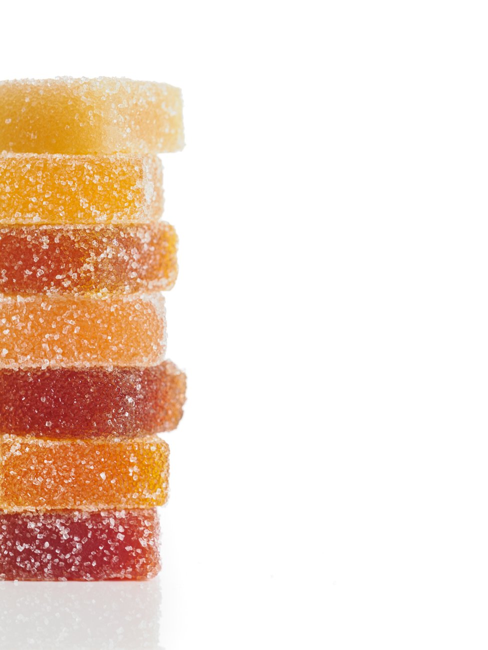 Stack of colorful gummy candies coated in sugar on a white background.