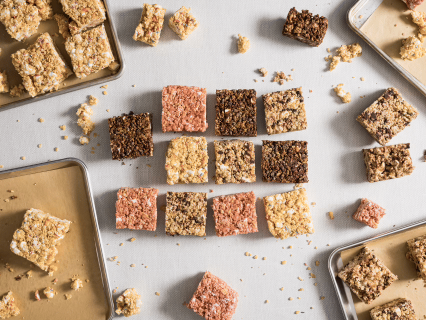 Assorted Fruity Pebbles rice krispie treats on a white surface, with some squares broken into crumbs.