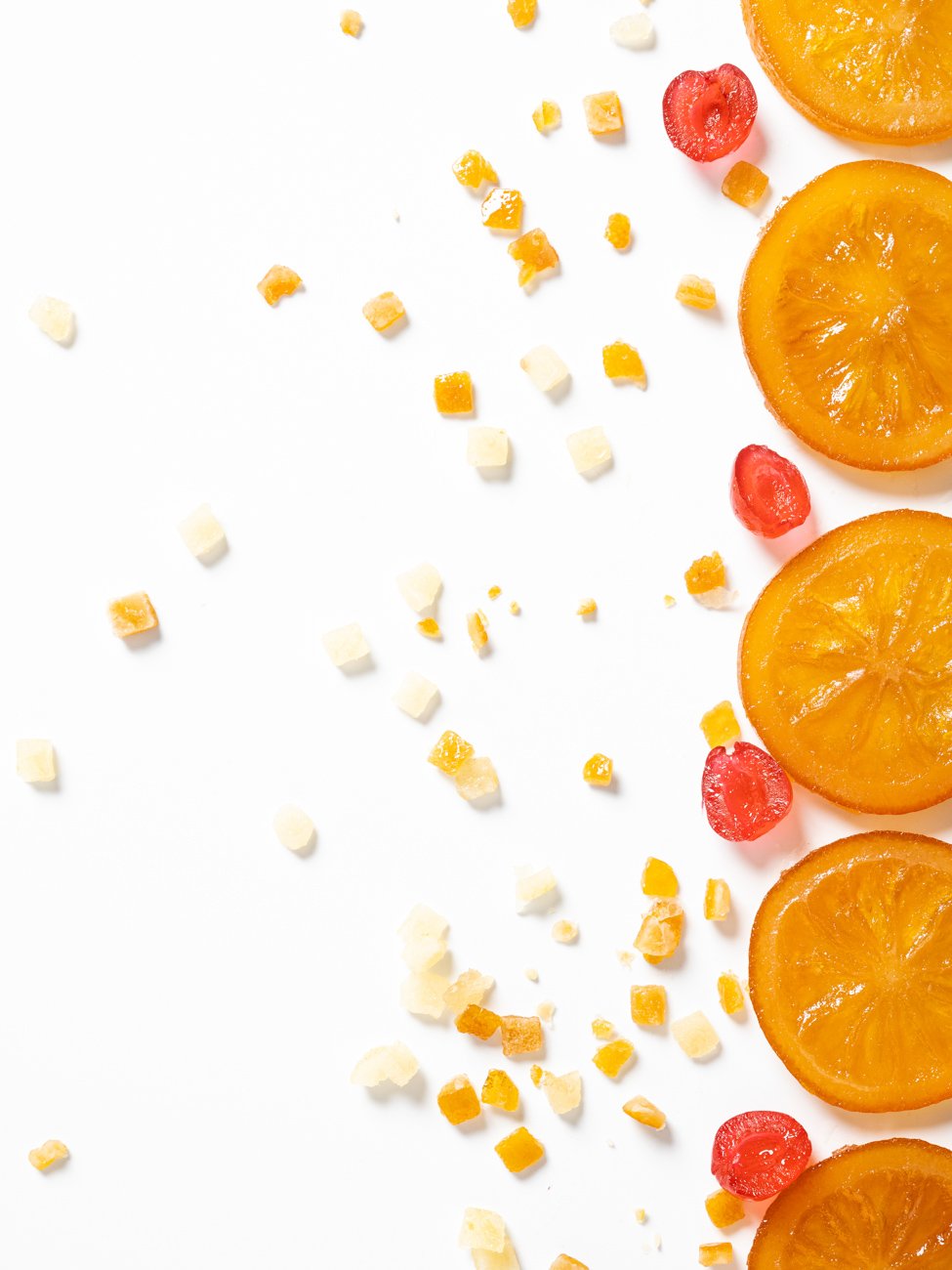 Sliced orange fruits on the right side, scattered small pieces of fruit and crumbs on a white background.