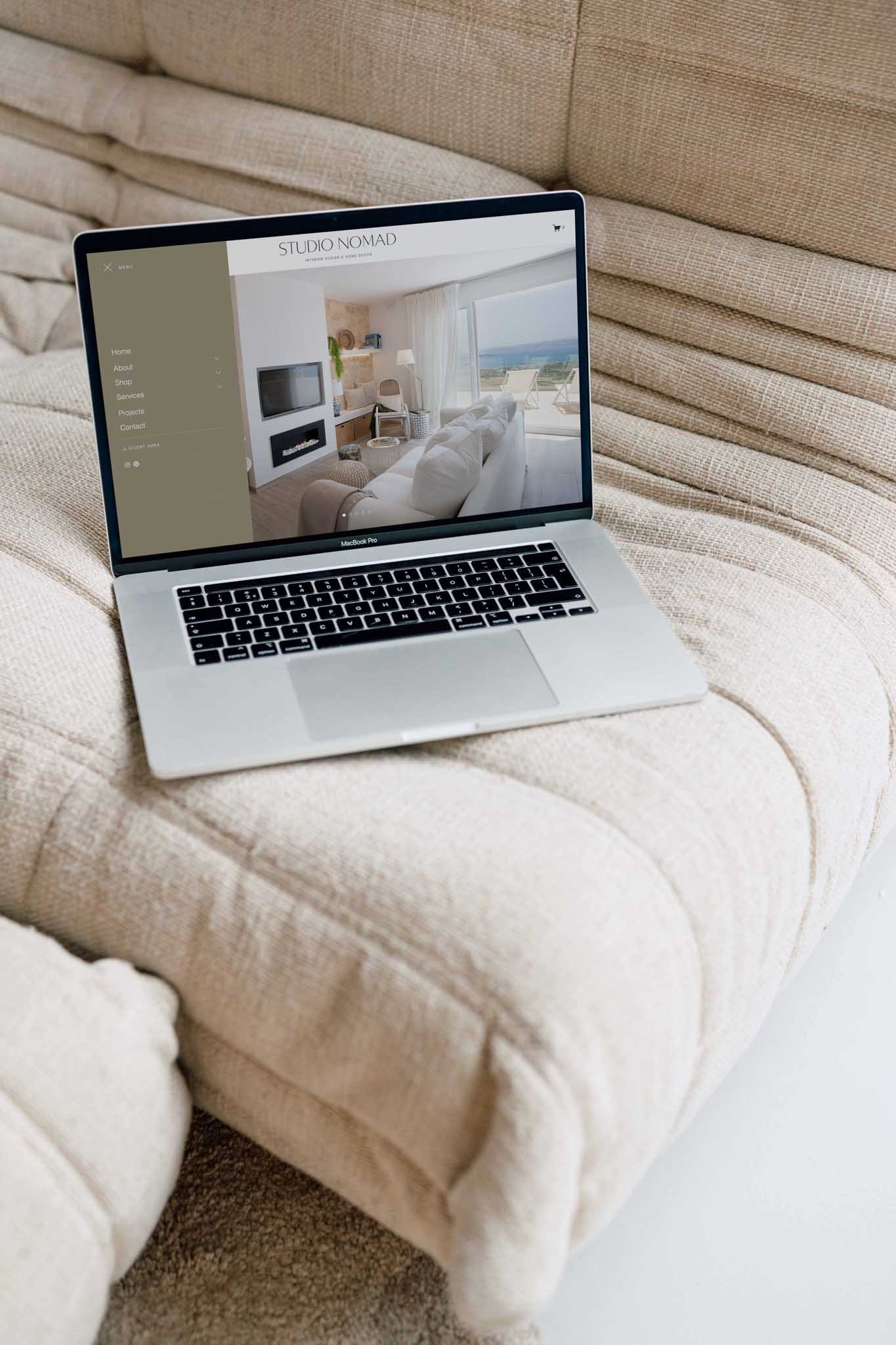 Open MacBook Pro displaying a website on a beige couch.