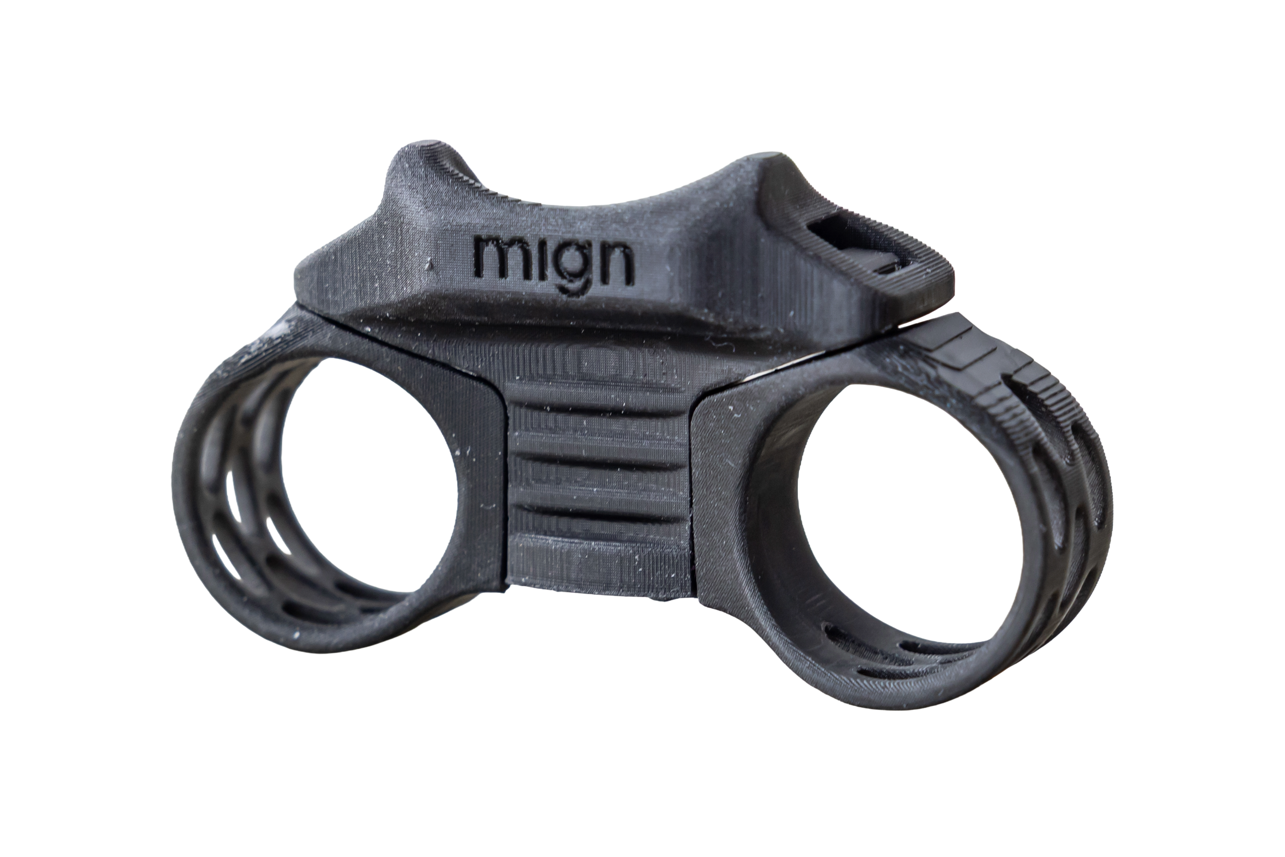 A black, 3D-printed dual-chambered object with the word 'mign' on top, featuring textured grips and a futuristic, mechanical design, placed on a reflective surface.