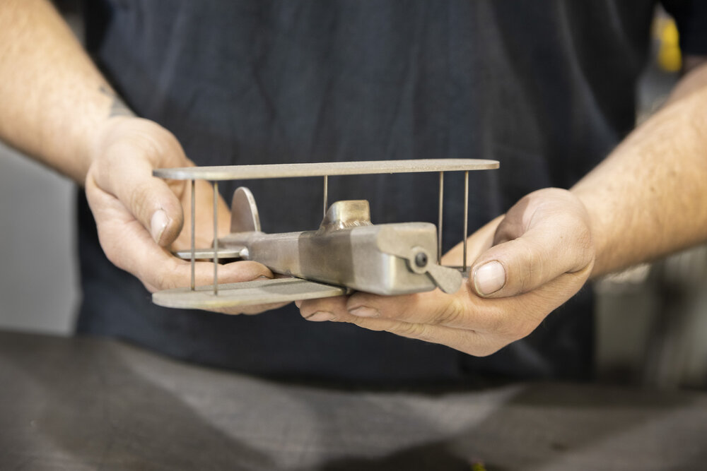 Billy displaying a welded toy plane he built 