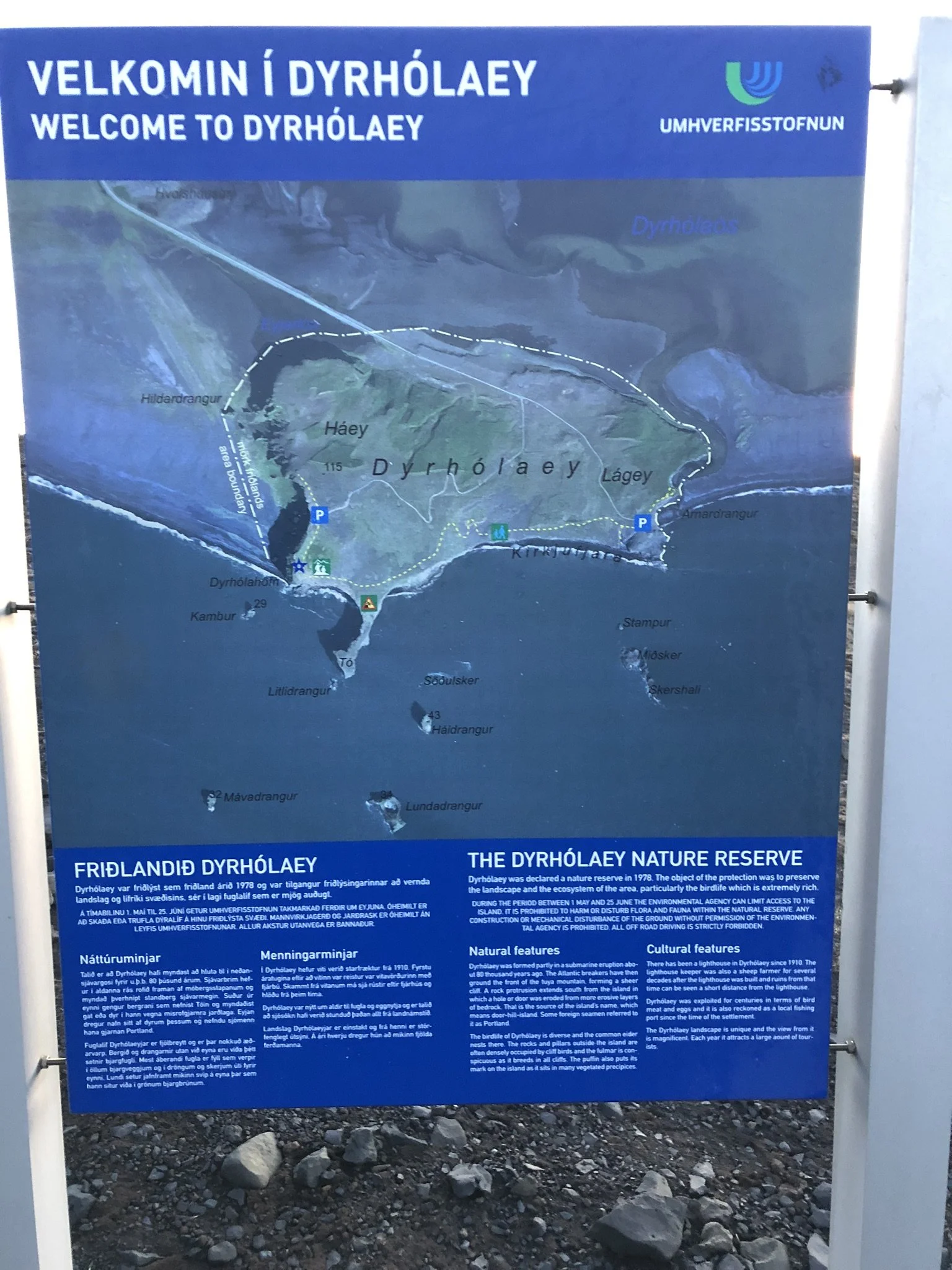 A map and informational sign welcoming visitors to Dyrhólaey, an Icelandic nature reserve. The sign includes a detailed map of the area, showing parking areas, trails, and surrounding islands. Text provides information about the reserve's history, na