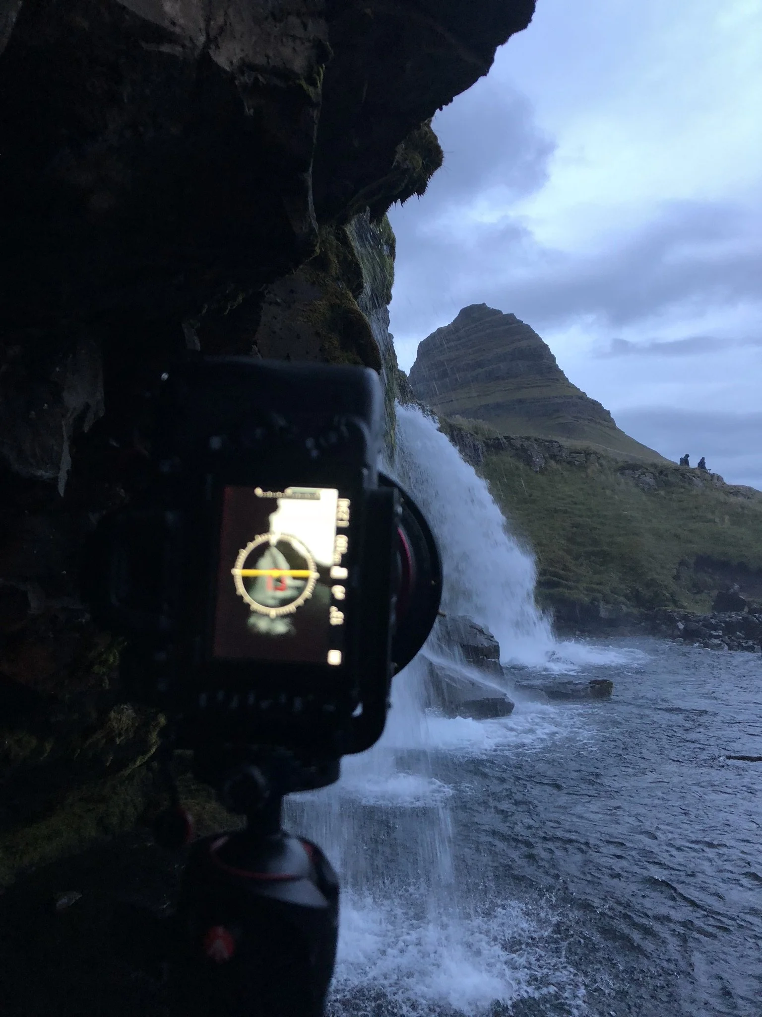 Camera capturing a waterfall at Kirkjufell mountain in Iceland during dusk.