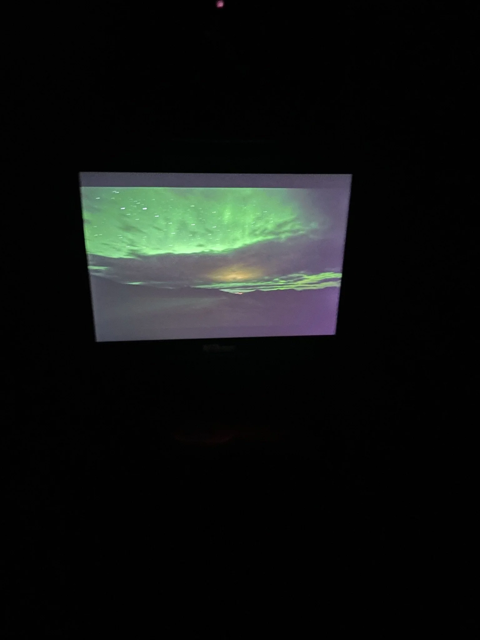 Display screen showing a photograph of the northern lights over a landscape at night.
