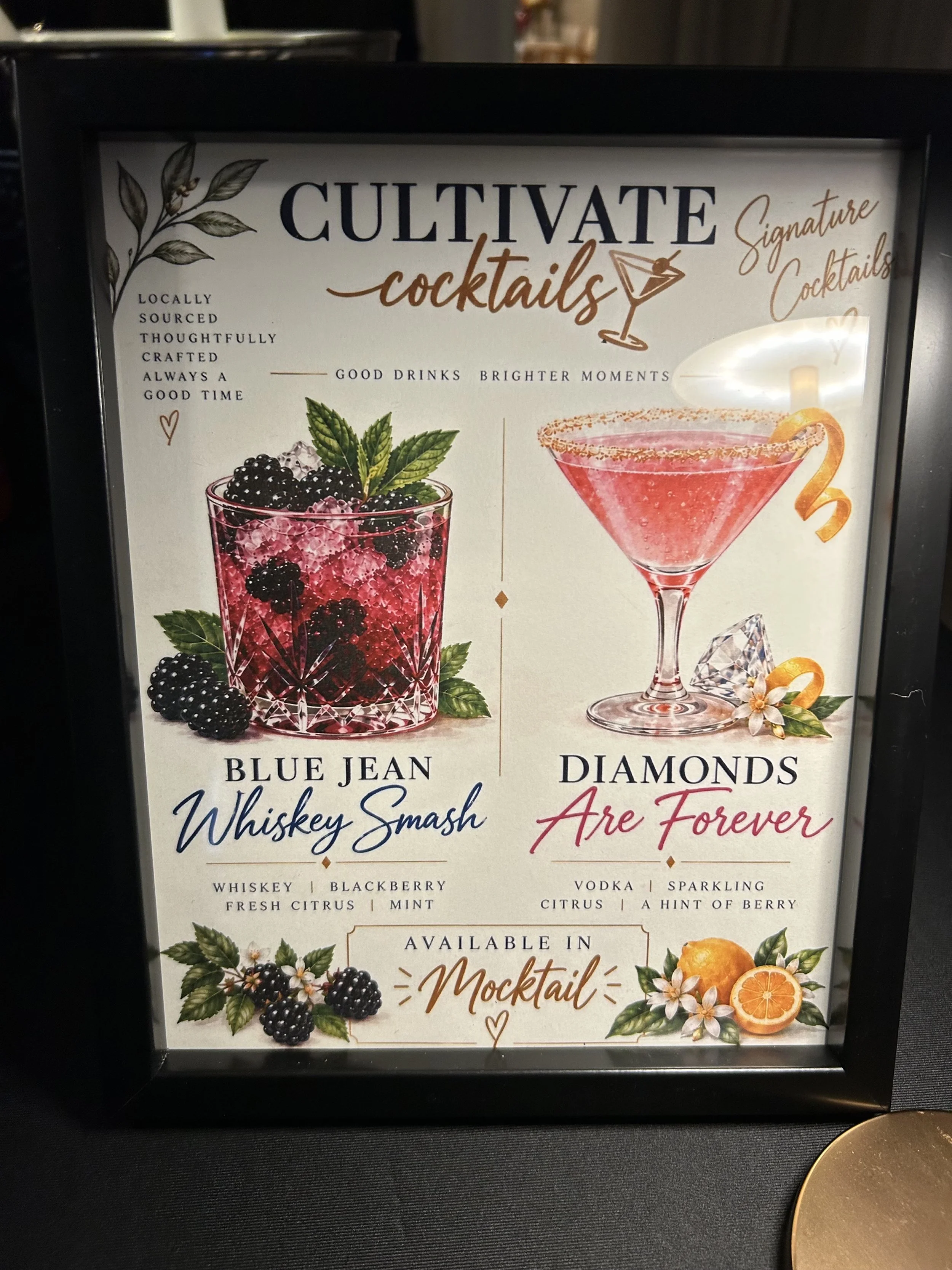 Menu display with illustrations of cocktails and berries, promoting locally sourced, handcrafted cocktails, including Whiskey Smash and Diamonds Are Forever, with ingredients listed.