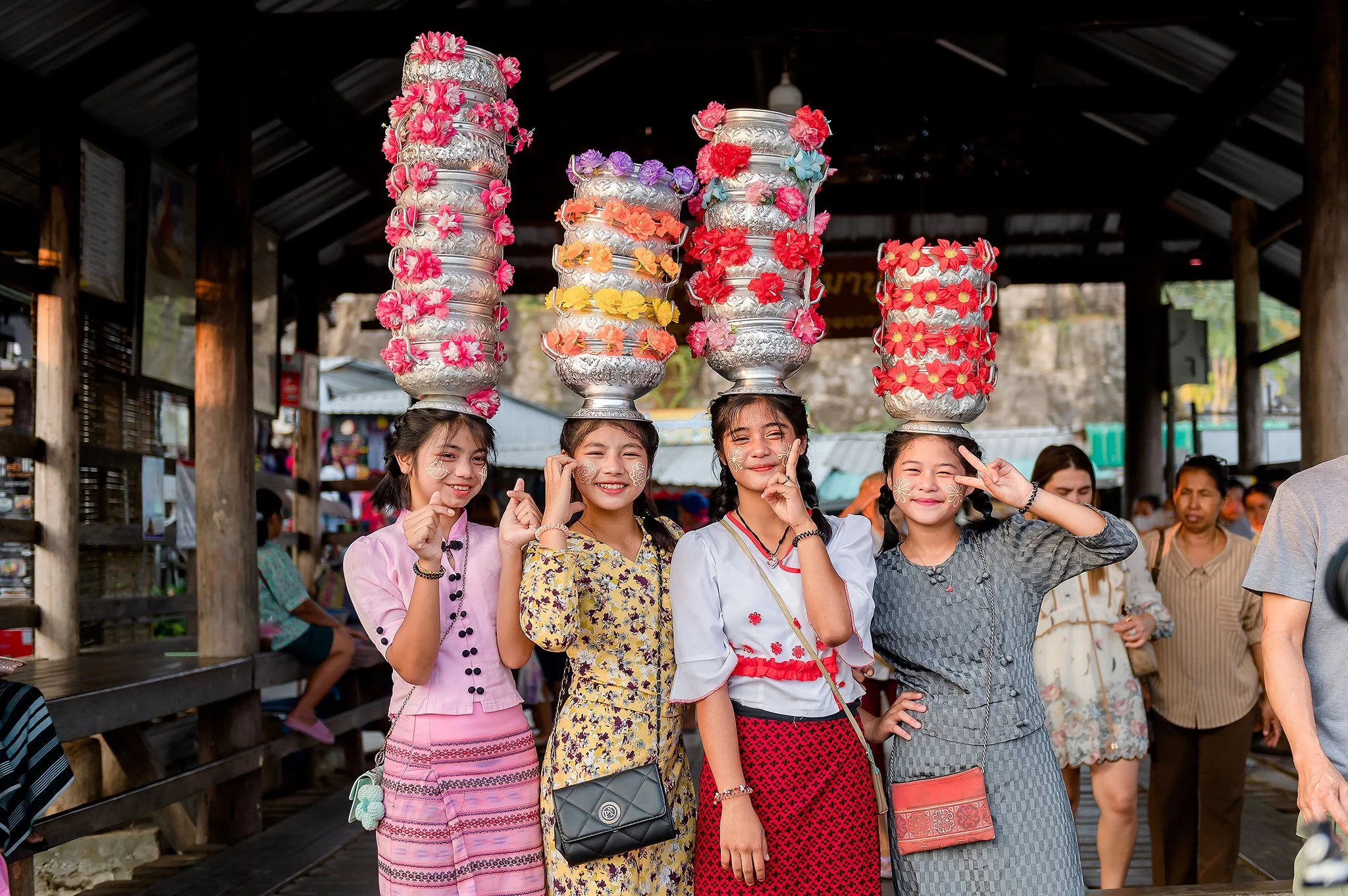 Mon villagers and tourists dressed in traditional clothes lined up along the street near Mon Bridge waiting for the morning almsgiving ceremony.