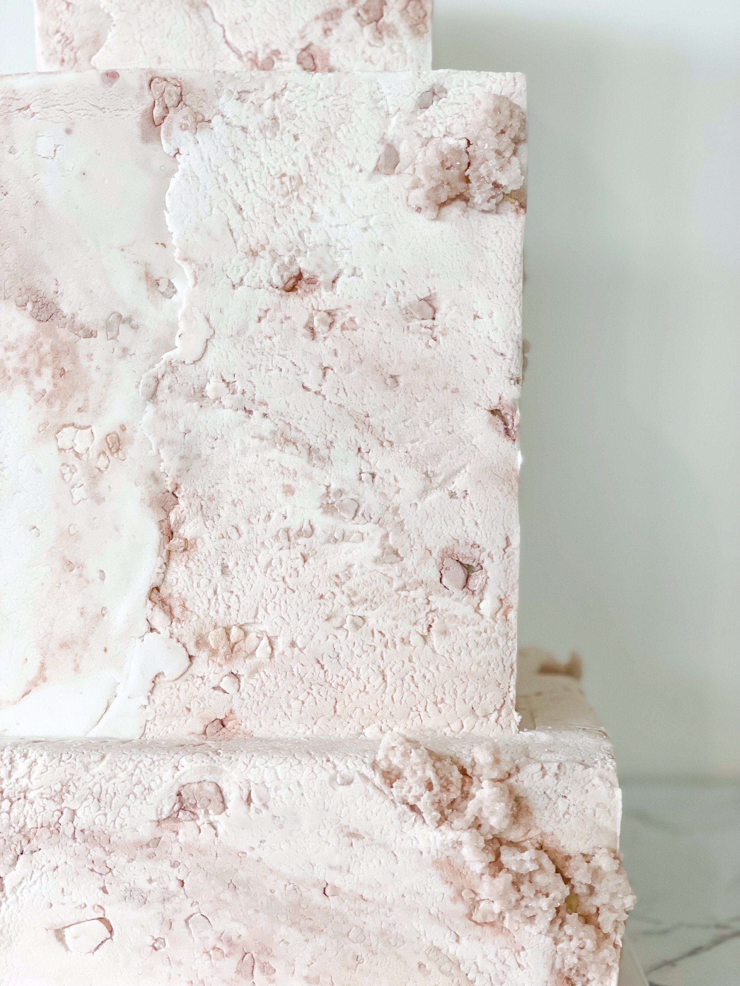Close-up of a textured, marble-patterned cake design in white and light pink.
