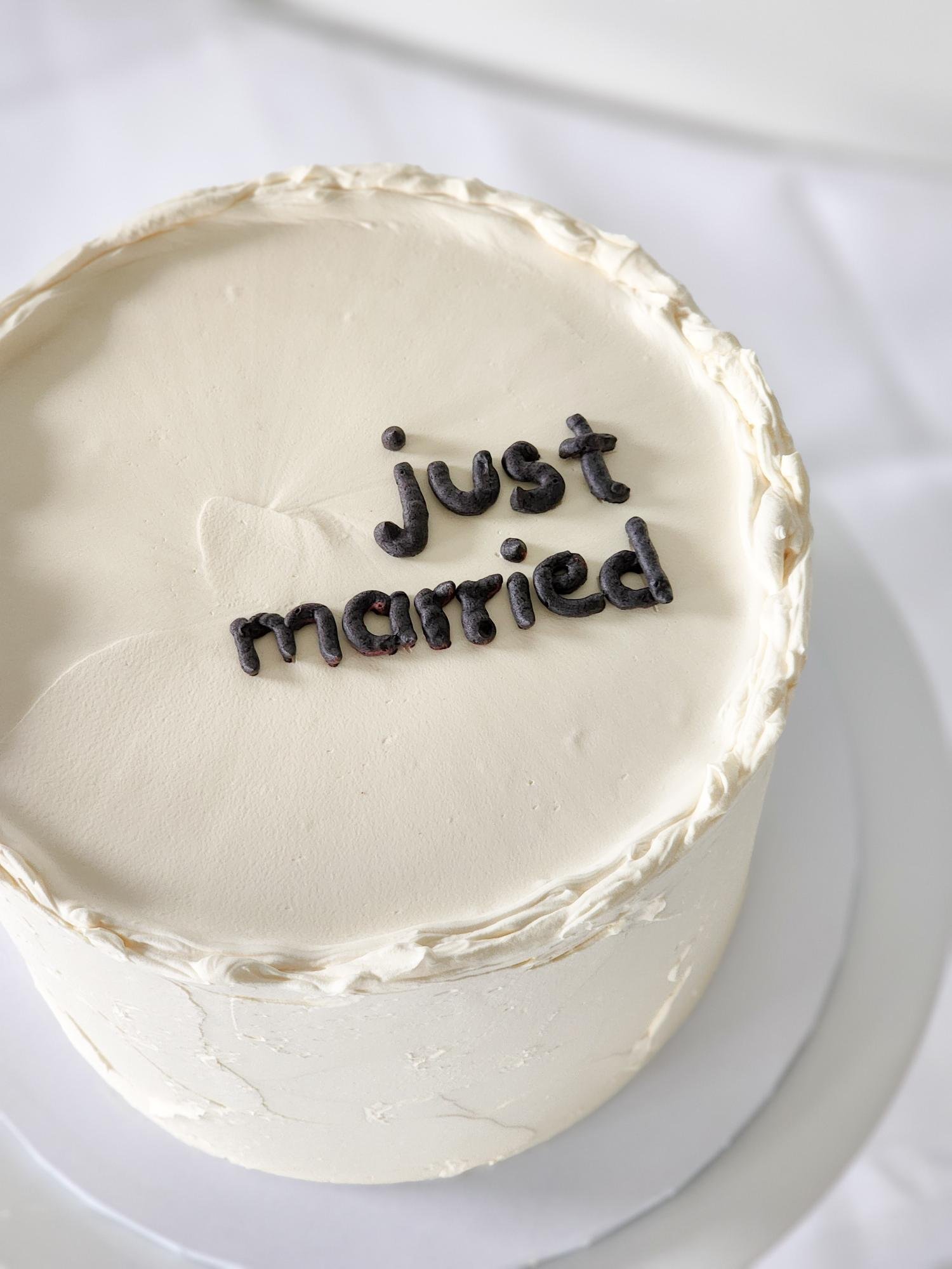 A white cake with a message made of black cereal letters that reads "just married."