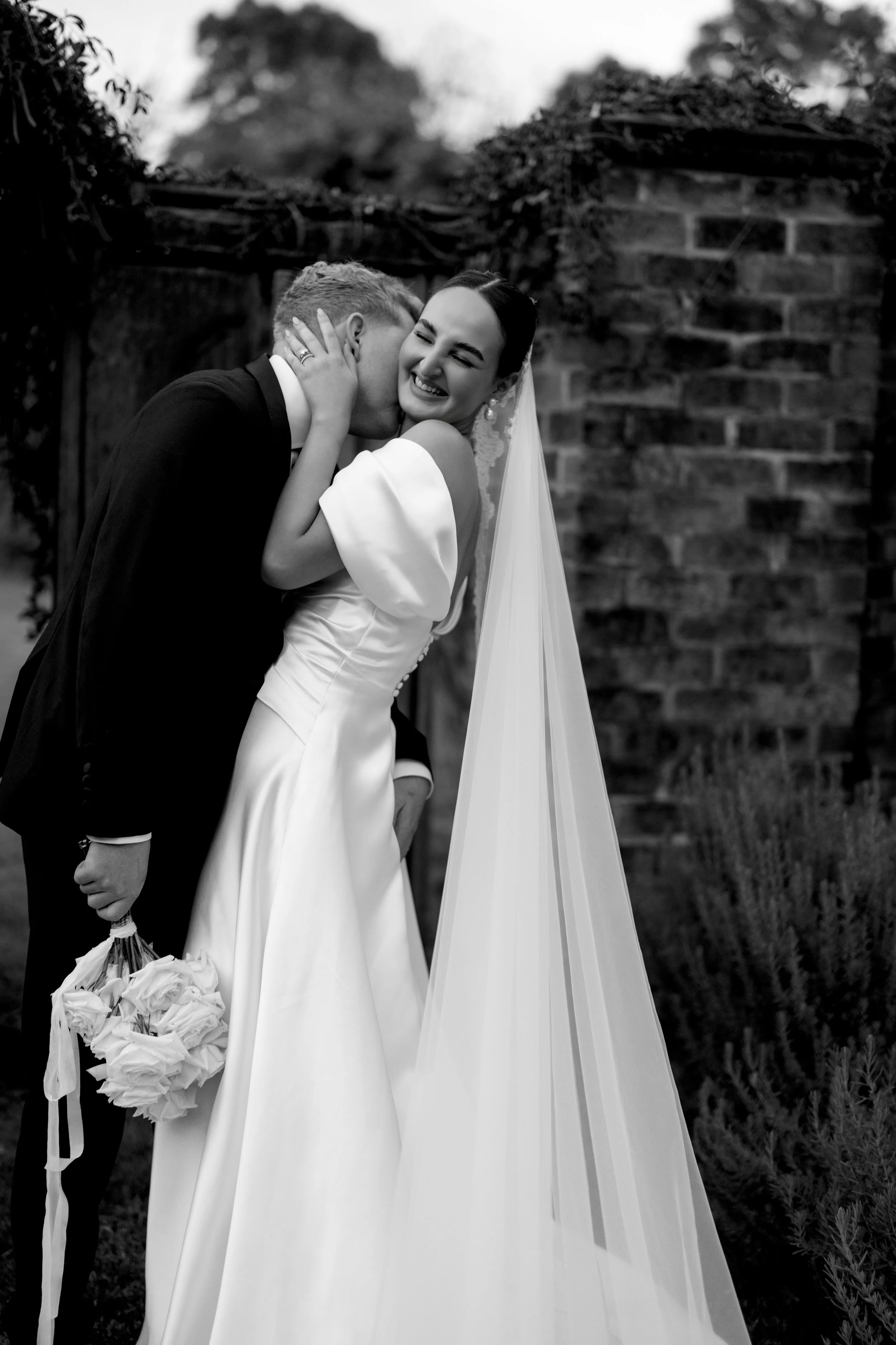 Bride and groom embracing, smiling, in black and white photo