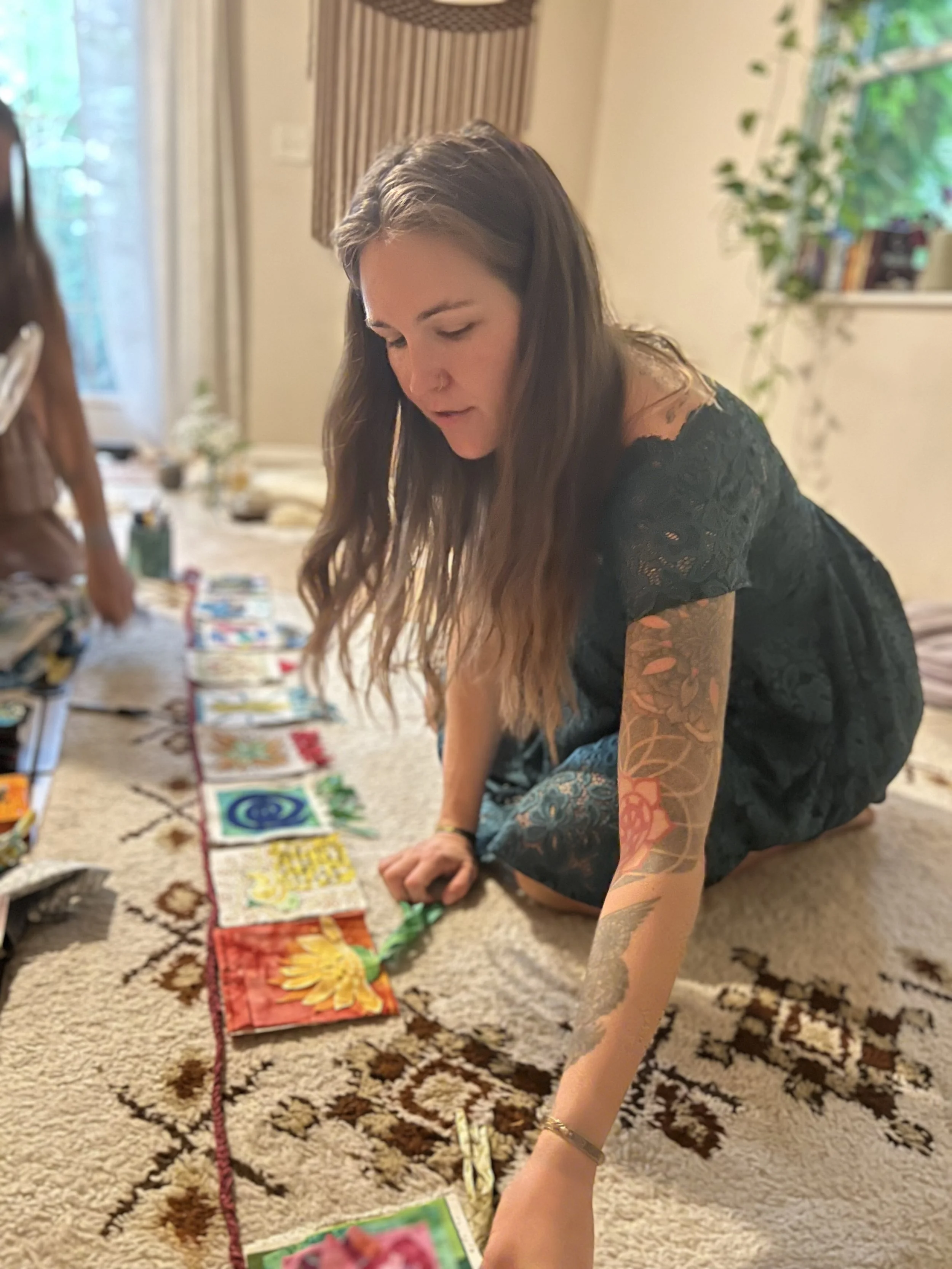 Birth doula Melissa Mascaro arranging handmade prayer flags during a mother blessing and birth preparation gathering.