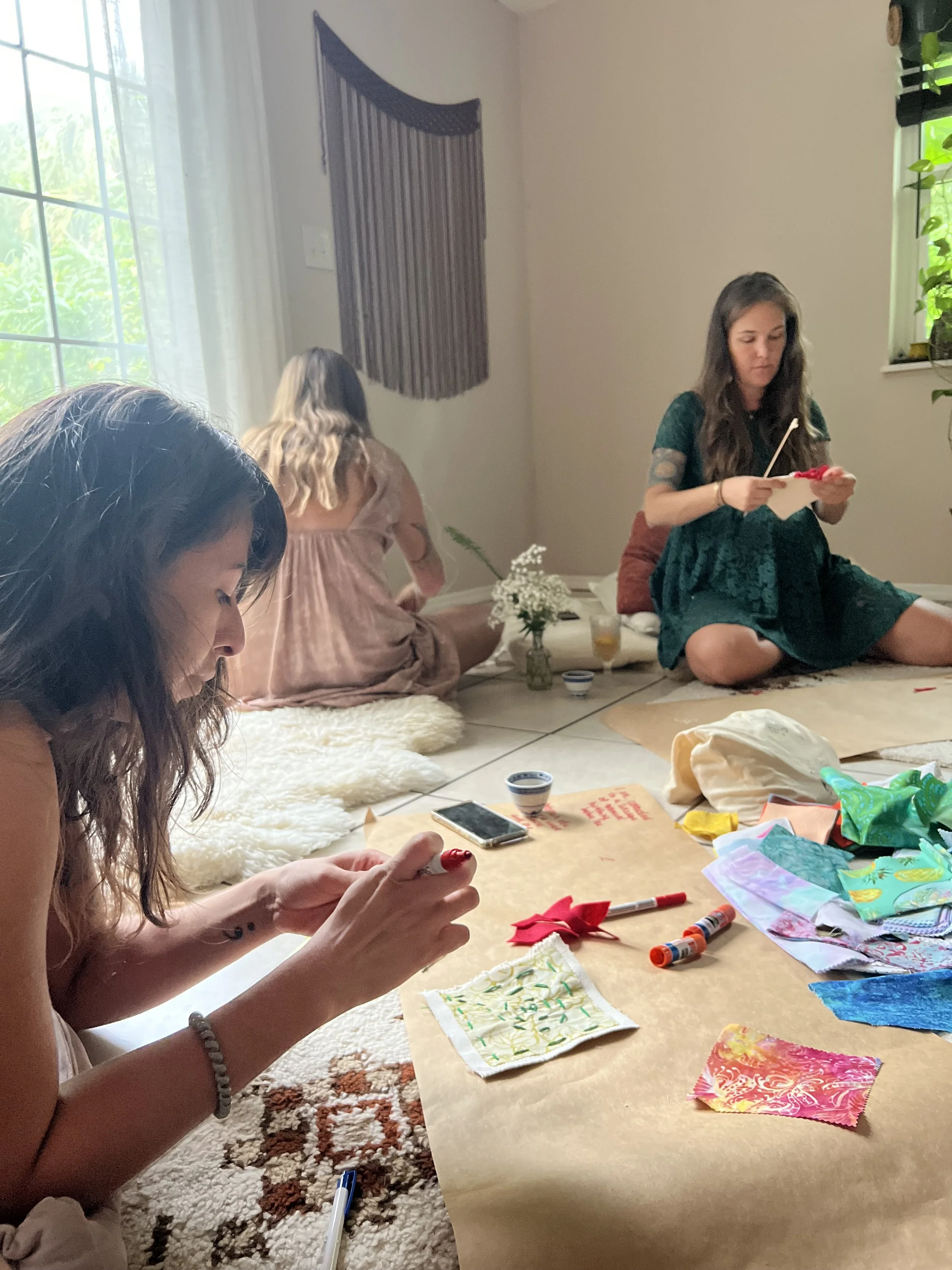 Women creating handmade prayer flags together during a mother blessing and prenatal gathering.
