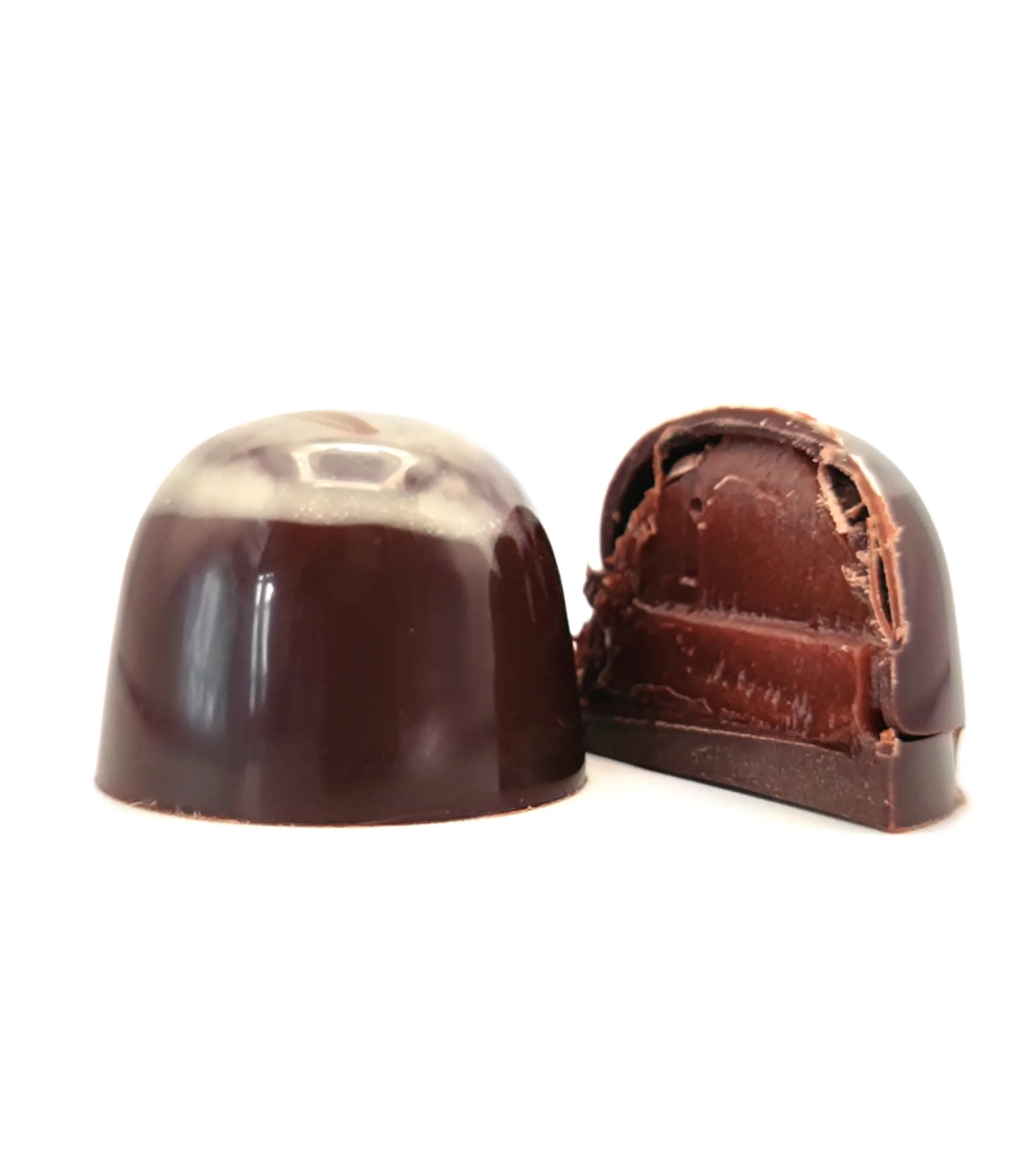 Two pieces of dark chocolate, one whole and one cut in half, showing a layered, creamy interior.