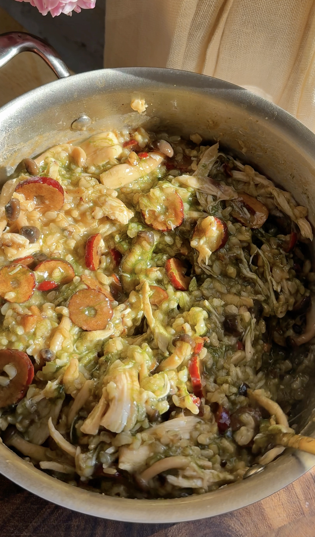 A close-up of finished Maesaengi-jook (Korean Seaweed Porridge) mixed with shredded chicken, shiitake mushrooms, and sliced red jujubes in a stainless steel pot.