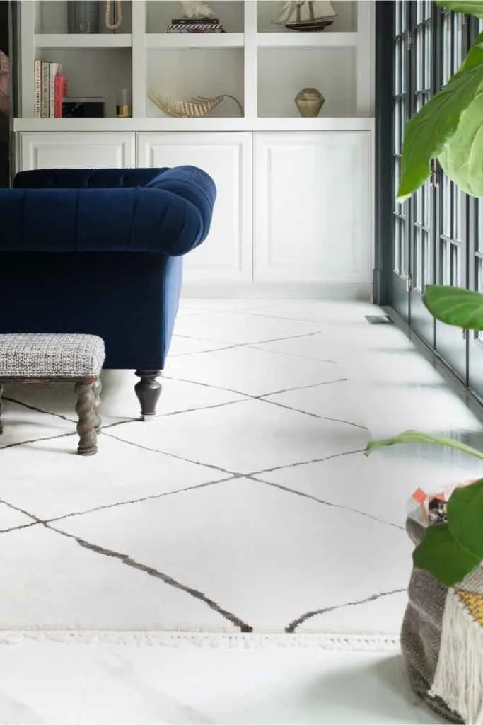 Luxurious living room with a bespoke white geometric rug complementing a navy blue armchair