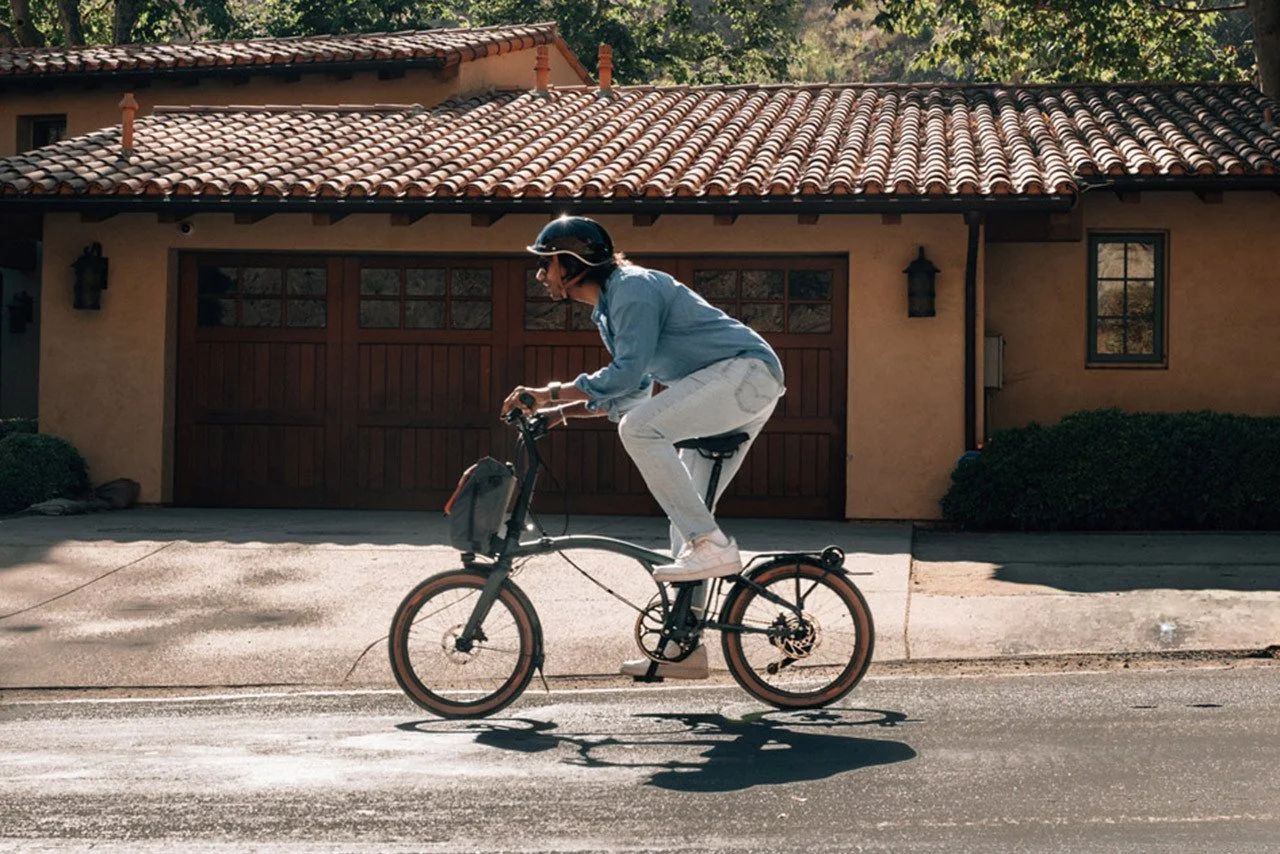 A person riding a Brompton G Line folding bike on the street.