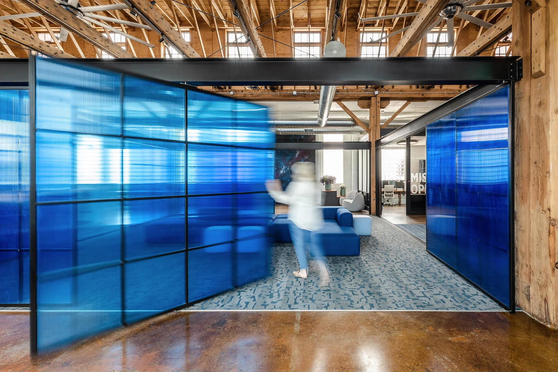Custom fabricated pivoting and sliding polycarbonate screens by Raw Creative, creating flexible workspace divisions within a timber loft office.