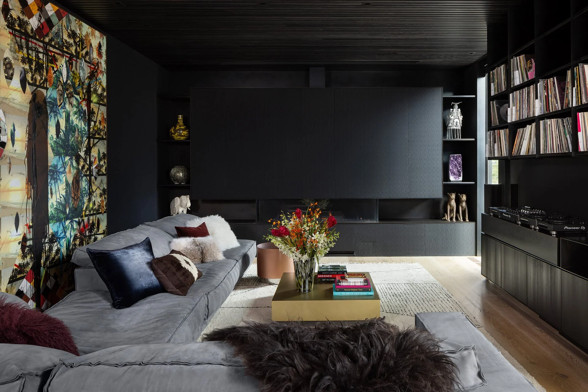 Art collector’s living space in a historic building renovation with custom millwork, blackened steel fireplace surround, integrated storage and dj wall, and gallery-style display