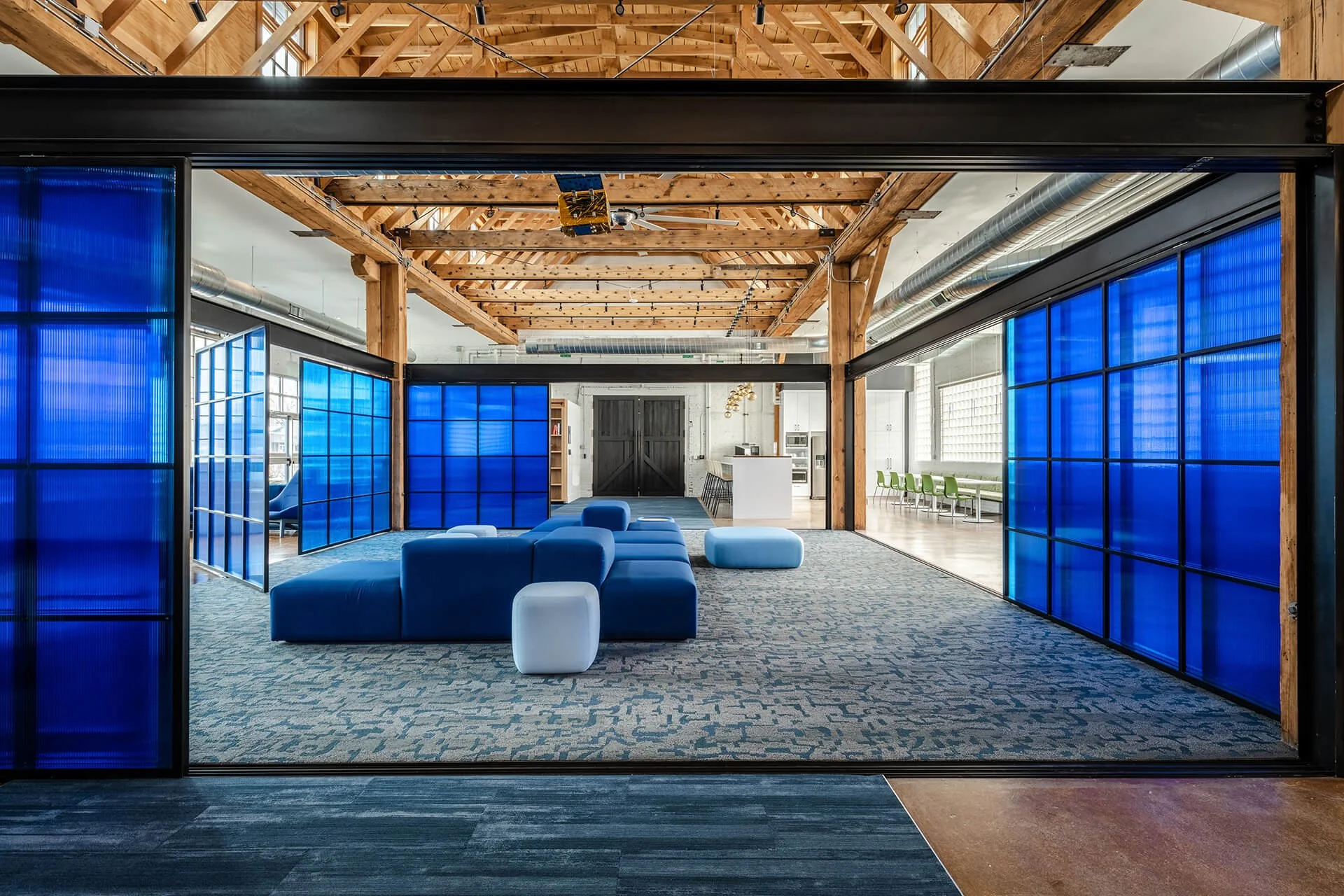 Custom steel-framed polycarbonate screens fabricated by Raw Creative, with pivoting and sliding panels defining collaborative workspaces in a converted warehouse office.