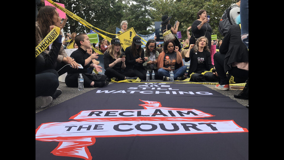 Protesters sit and block First Street NE in front of the Supreme Court.