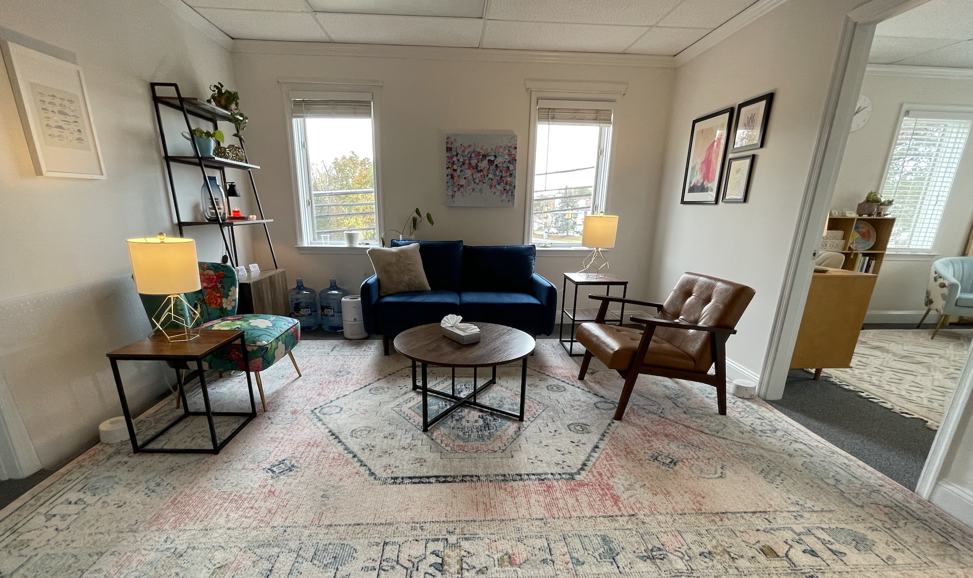 waiting room with blue couch brown chair and windows