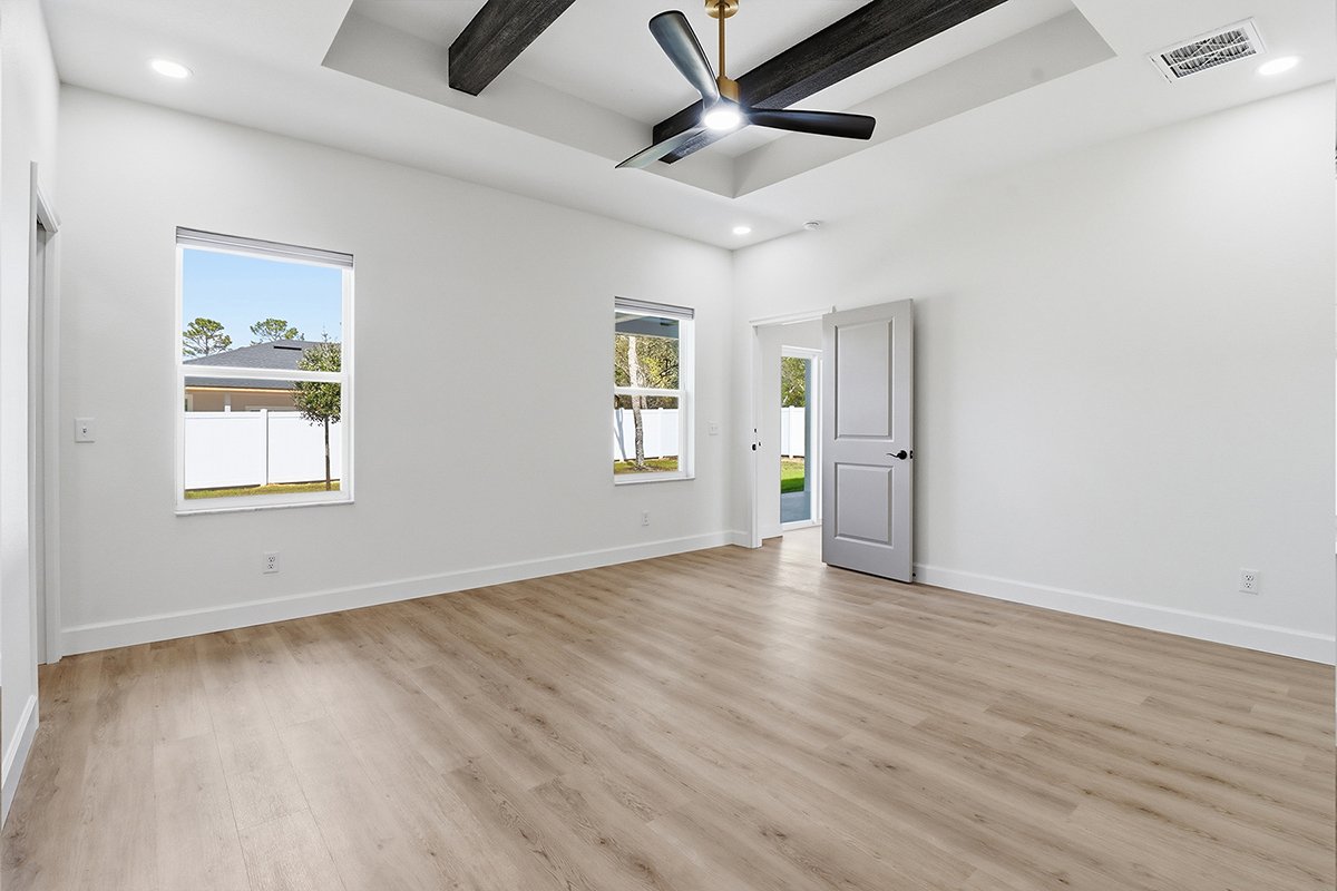 Empty room with white walls, light wood flooring, two windows, a door, recessed ceiling lights, and a ceiling fan.
