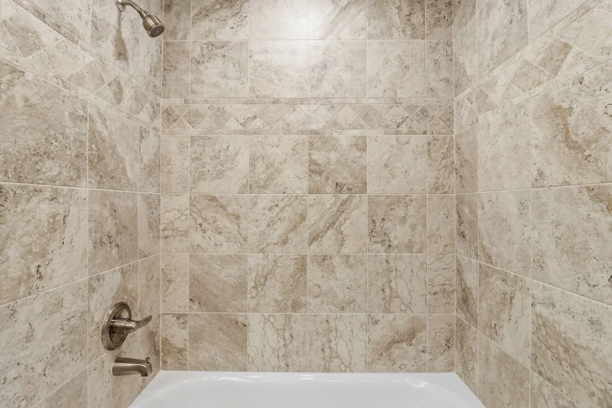 Empty shower with tiled walls and a showerhead.