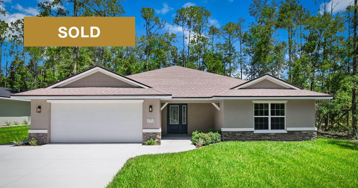 Newly constructed home with beige stucco exterior with brown stone accents and covered front porch