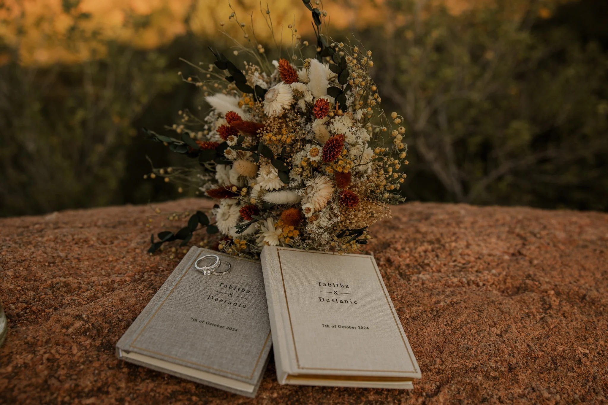 Elopement vow books, wedding rings, and bouquet on red rock at Garden of the Gods in Colorado Springs.