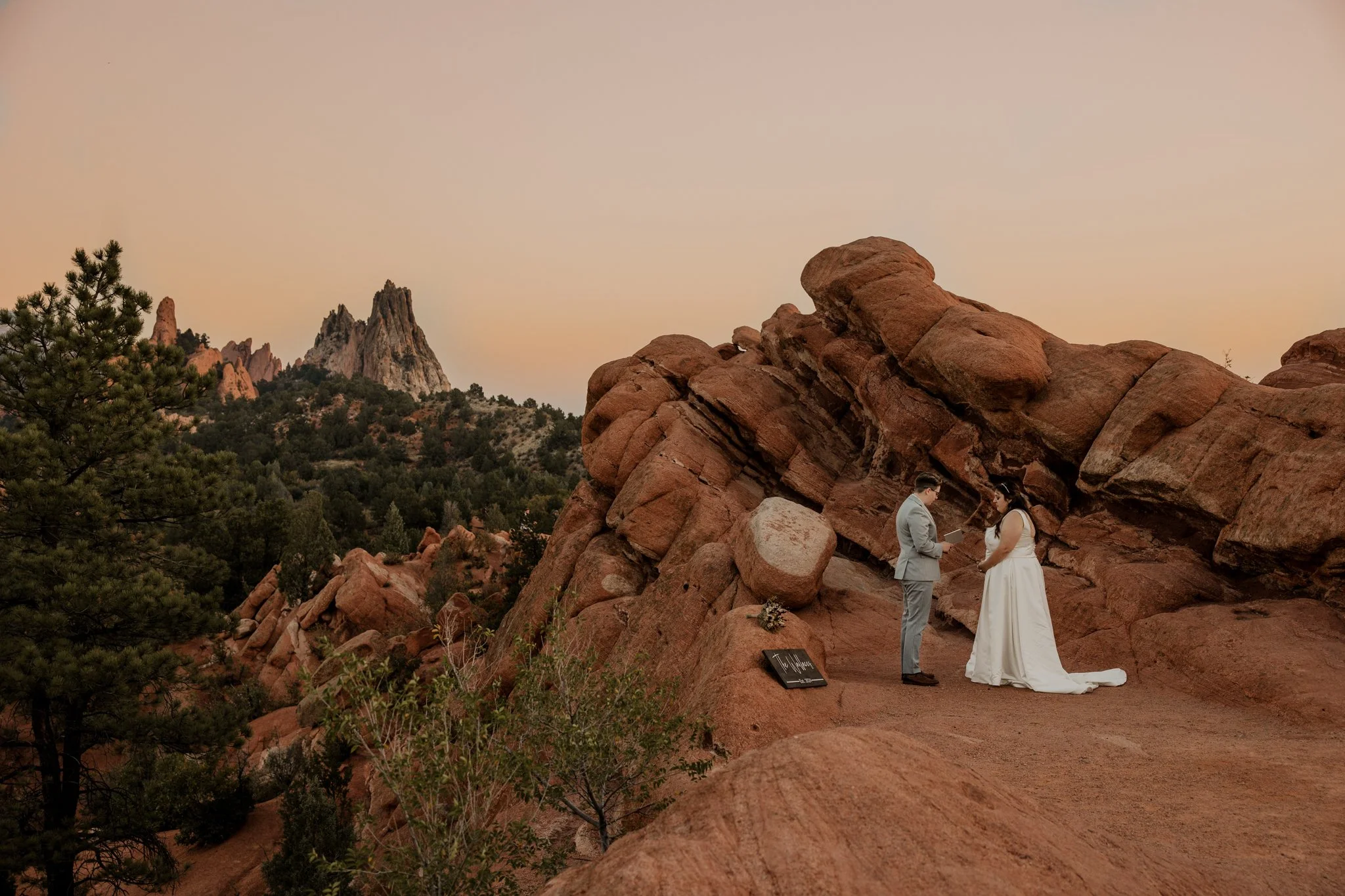 Intimate sunrise elopement at Garden of the Gods in Colorado Springs with couple reading vows on red rock overlook.