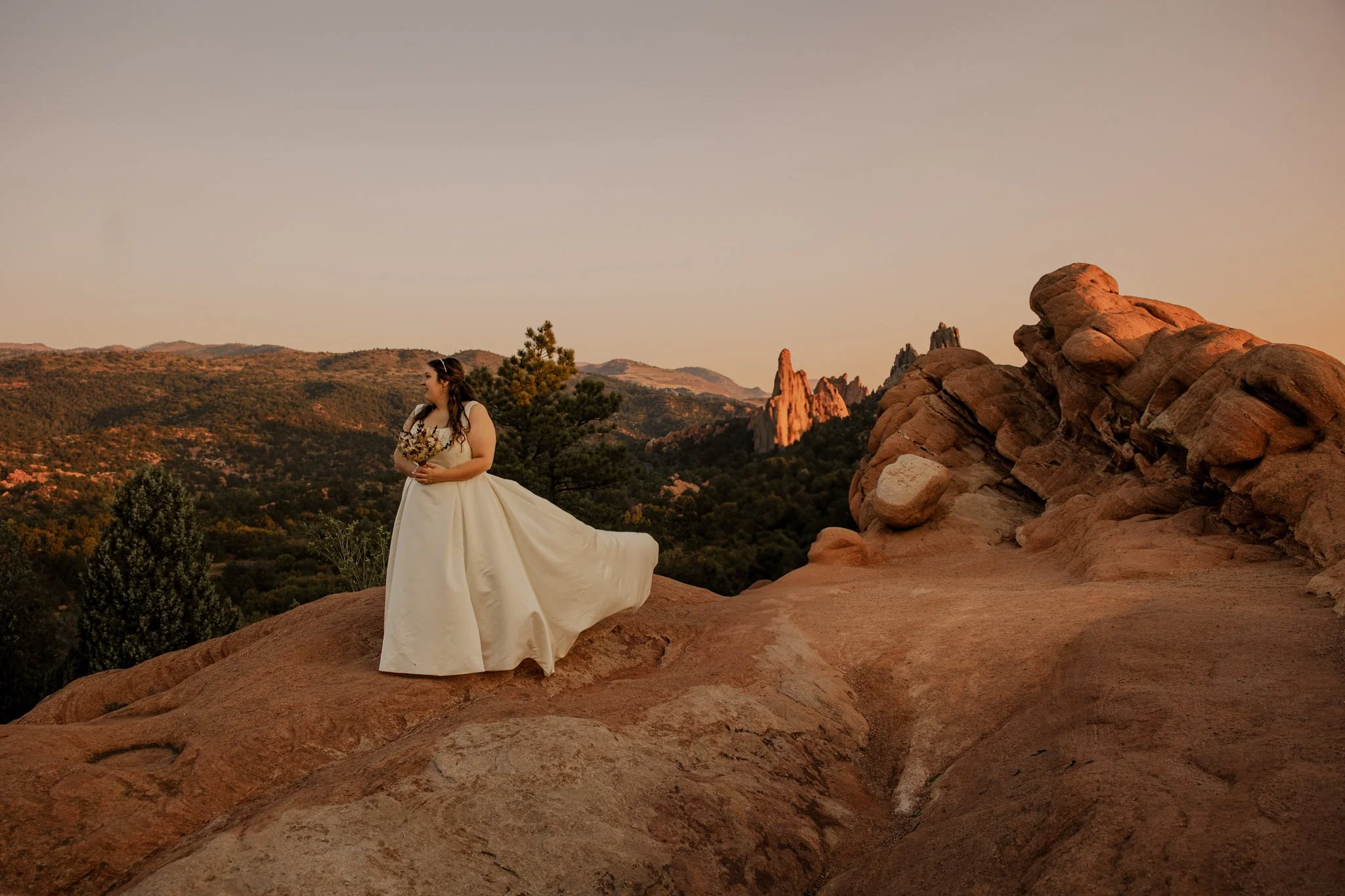 Bride standing on red rock overlook during a sunrise elopement at Garden of the Gods in Colorado Springs.