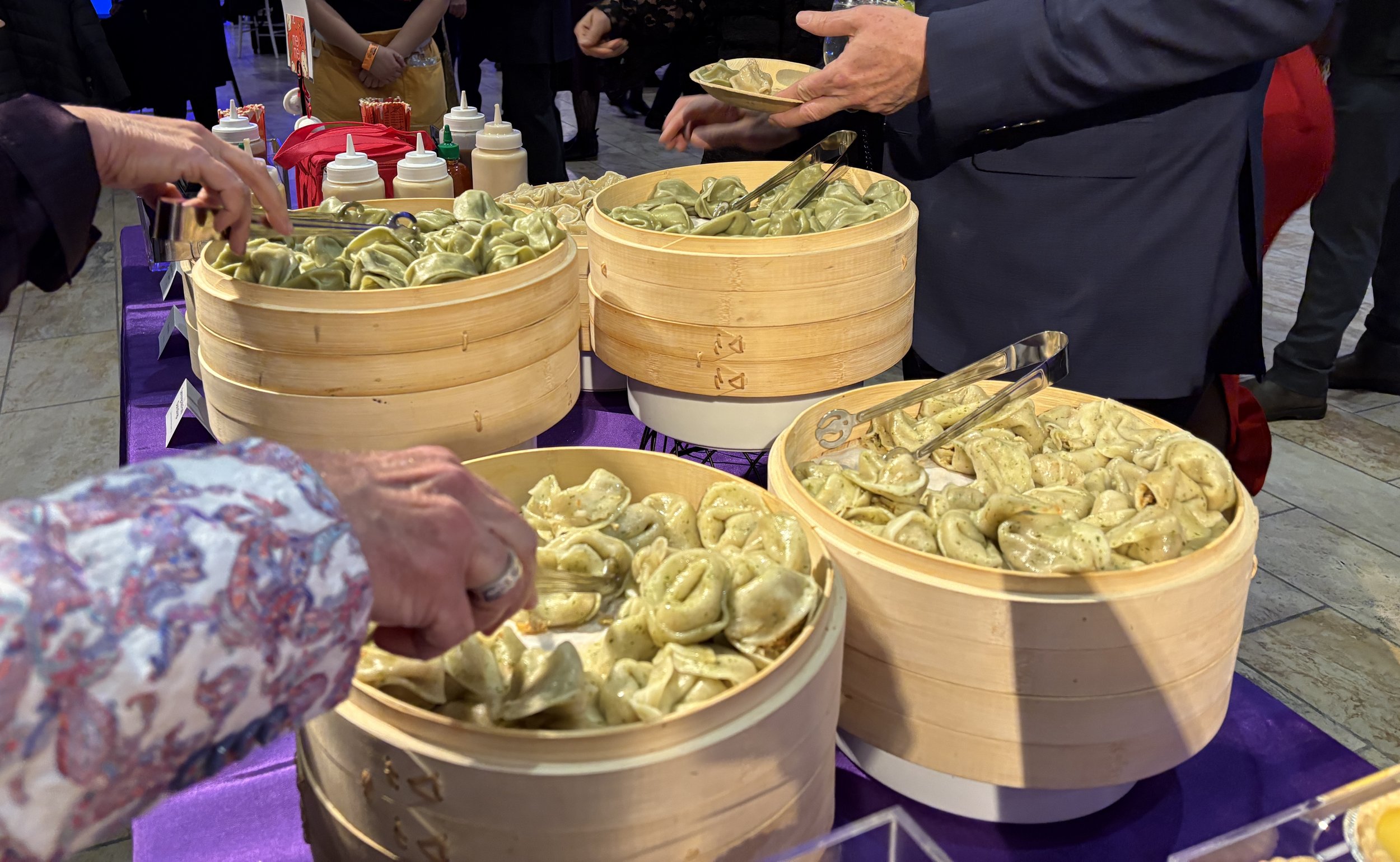 2 people serving themselves mei mei dumplings from steaming baskets at mayor wu's inauguration