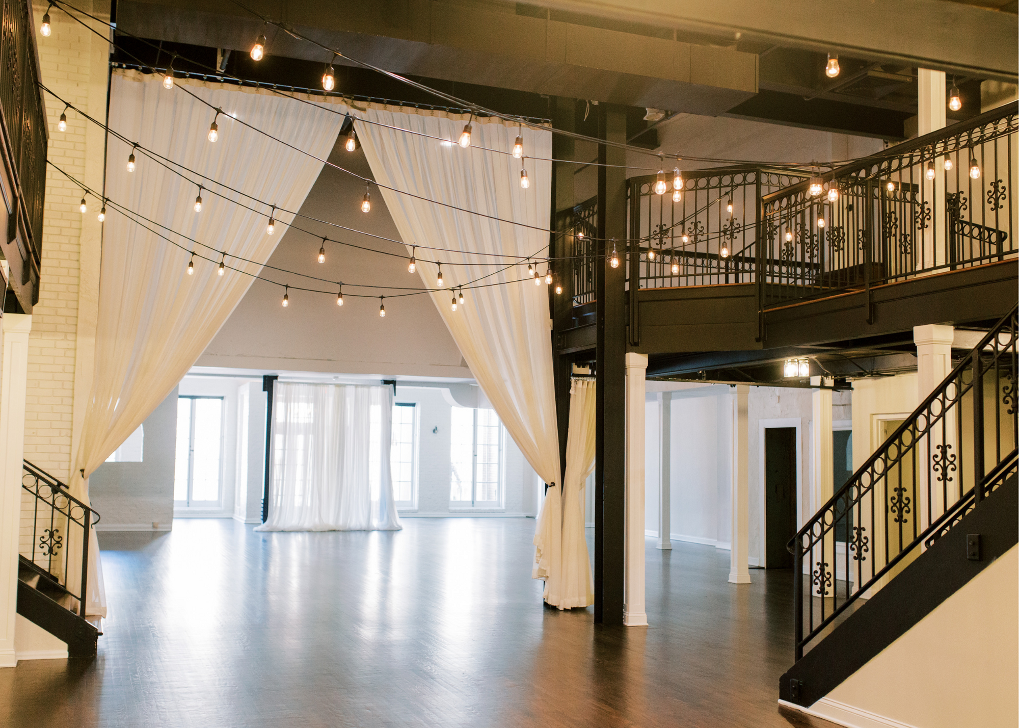 Dimmable bistro lights hang like stars our event spaces. Elegant drapery can is available for additional decor and to conceal reception tables and decor during a ceremony.