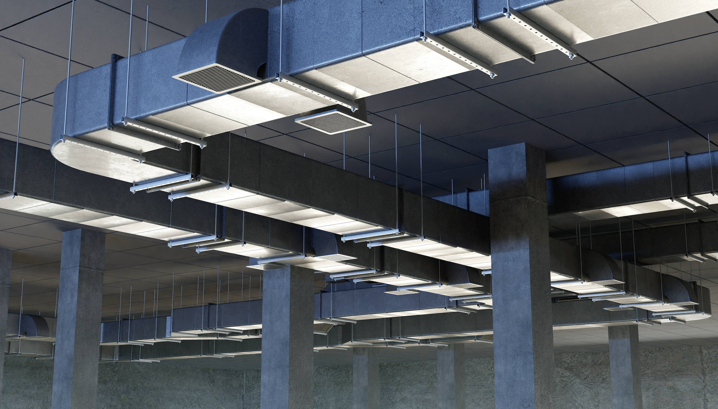 Interior view of an industrial ceiling with exposed ducts, vents, and structural supports.