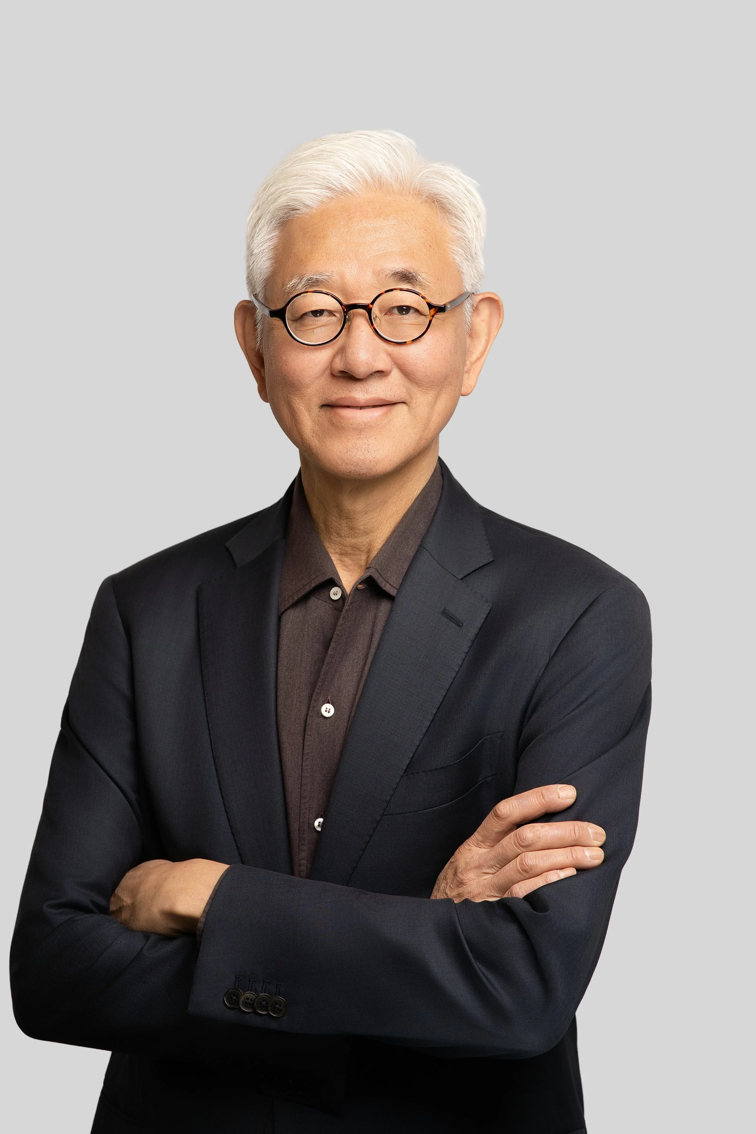 Business headshot of a man with a gray blazer against an off-white background taken at 415Headshots' Sacramento studio