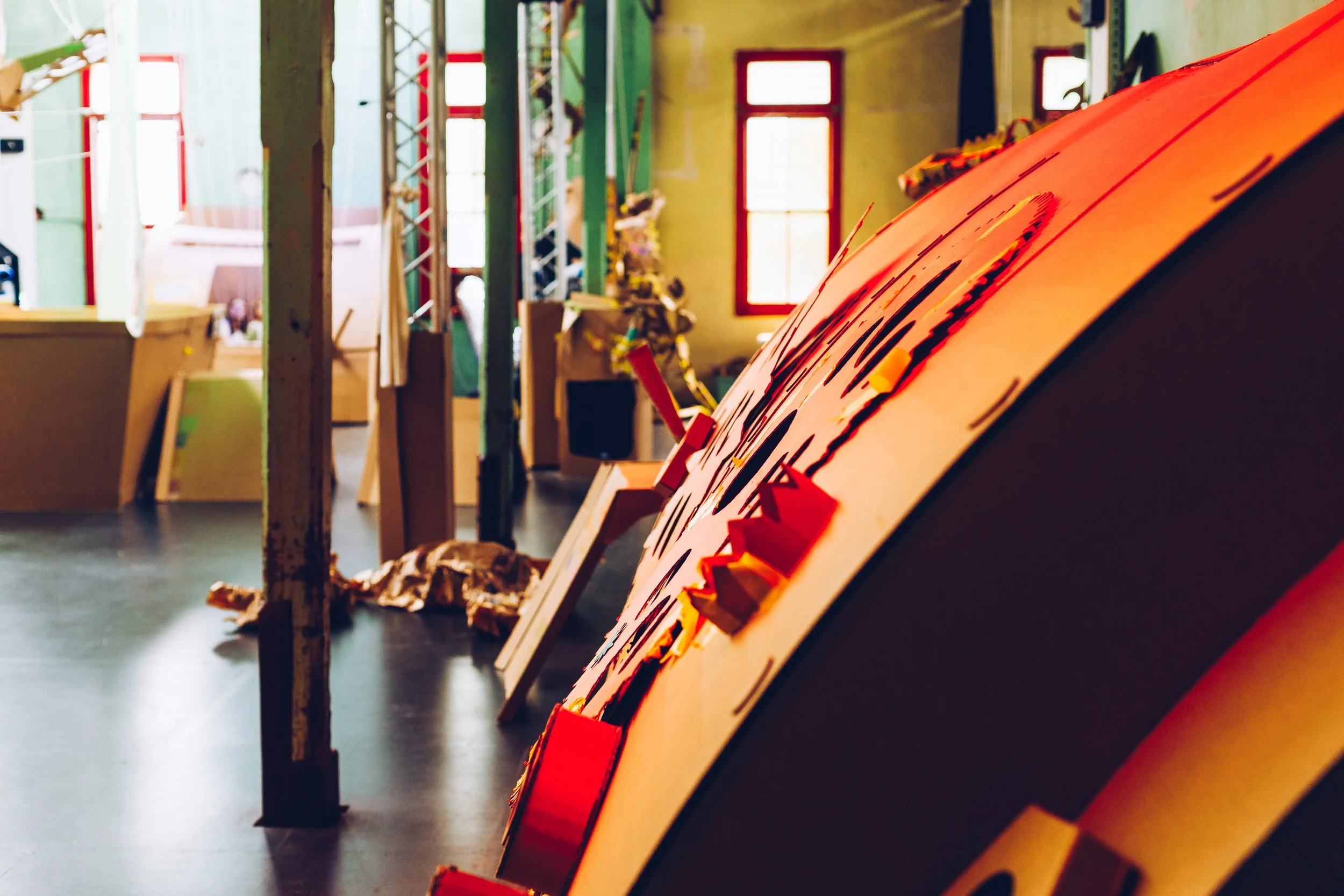 Gallery of various colorful contemporary artworks and installations on display in an art gallery with windows letting in natural light.