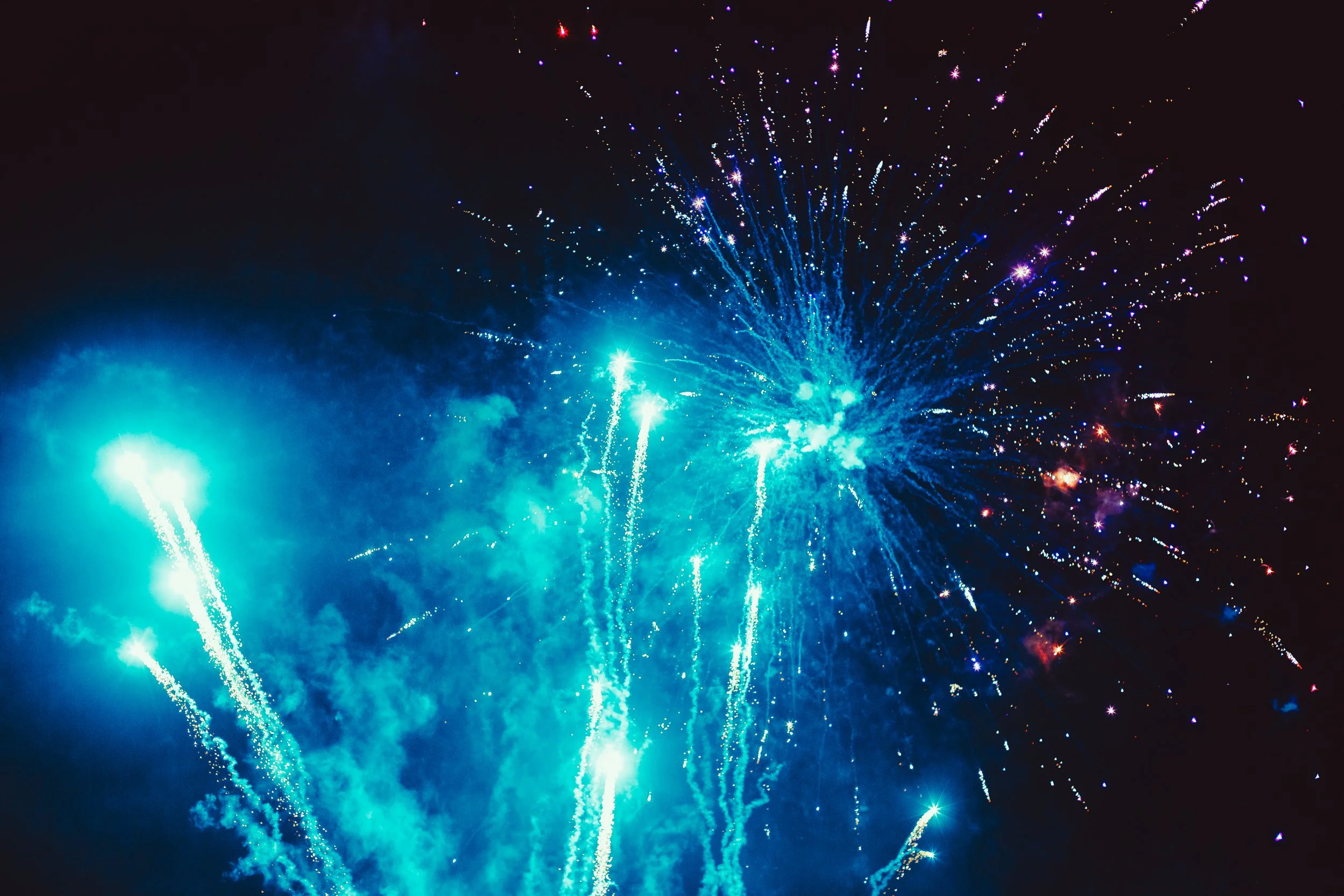 Bright blue fireworks exploding in the night sky with streaks and sparkles.