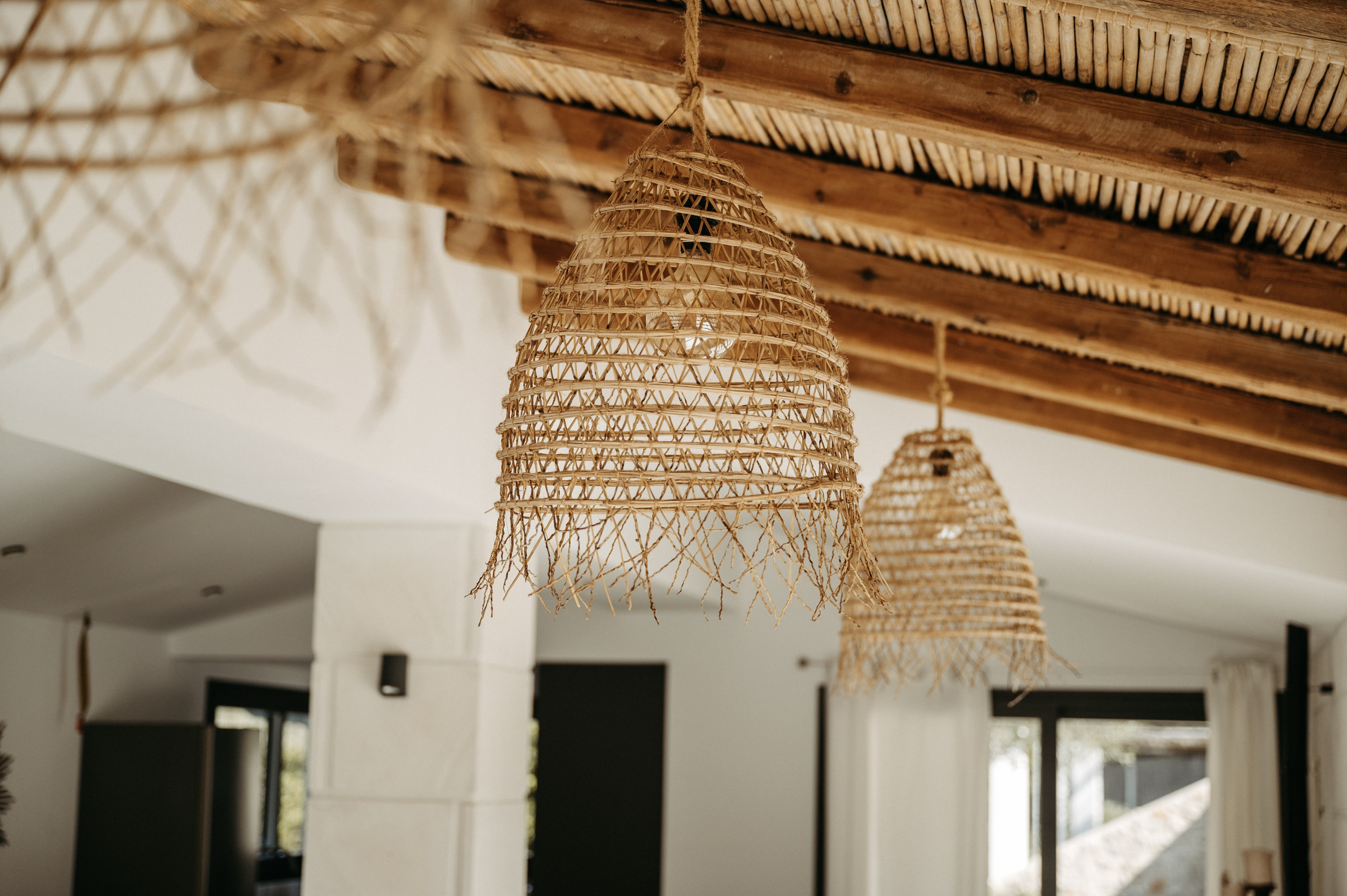 Woven rattan light fixtures hanging from a wooden ceiling.