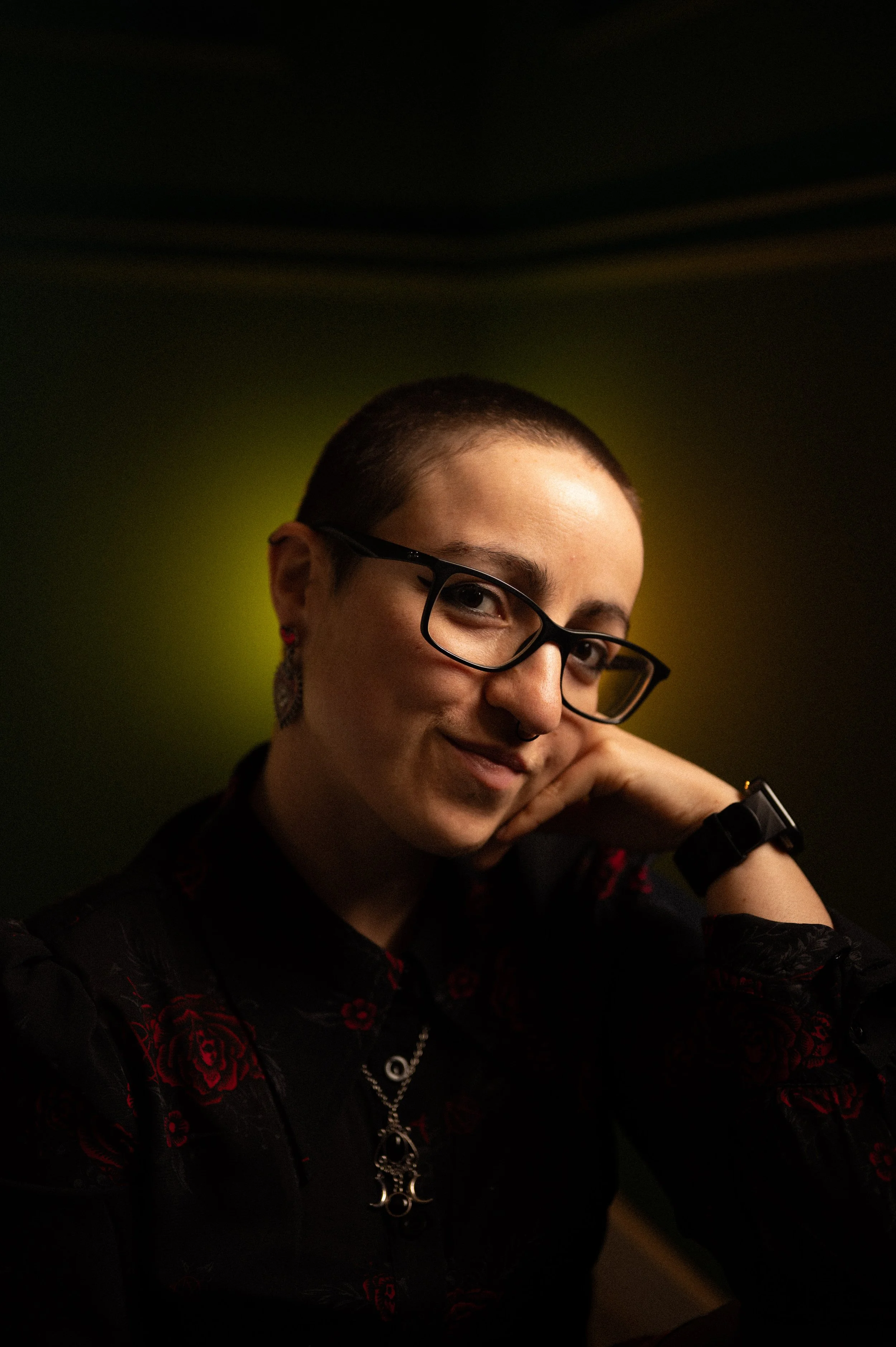 Lisbon couples photographer, a girl in a dark green background with a yellow light behind her smiling at the camera