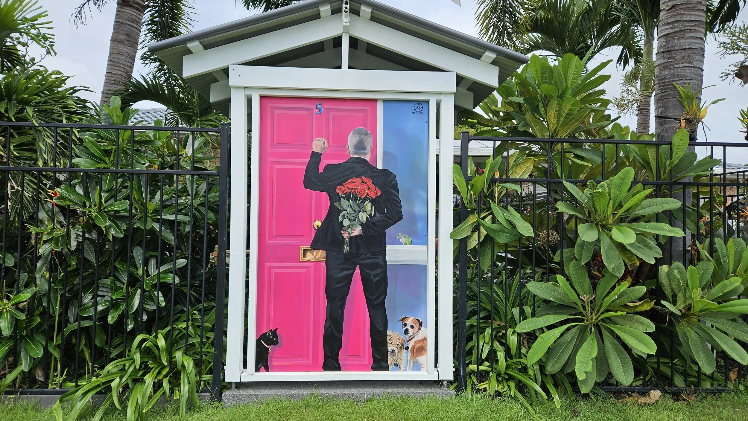 man knocking on pink door holding red roses behind his back