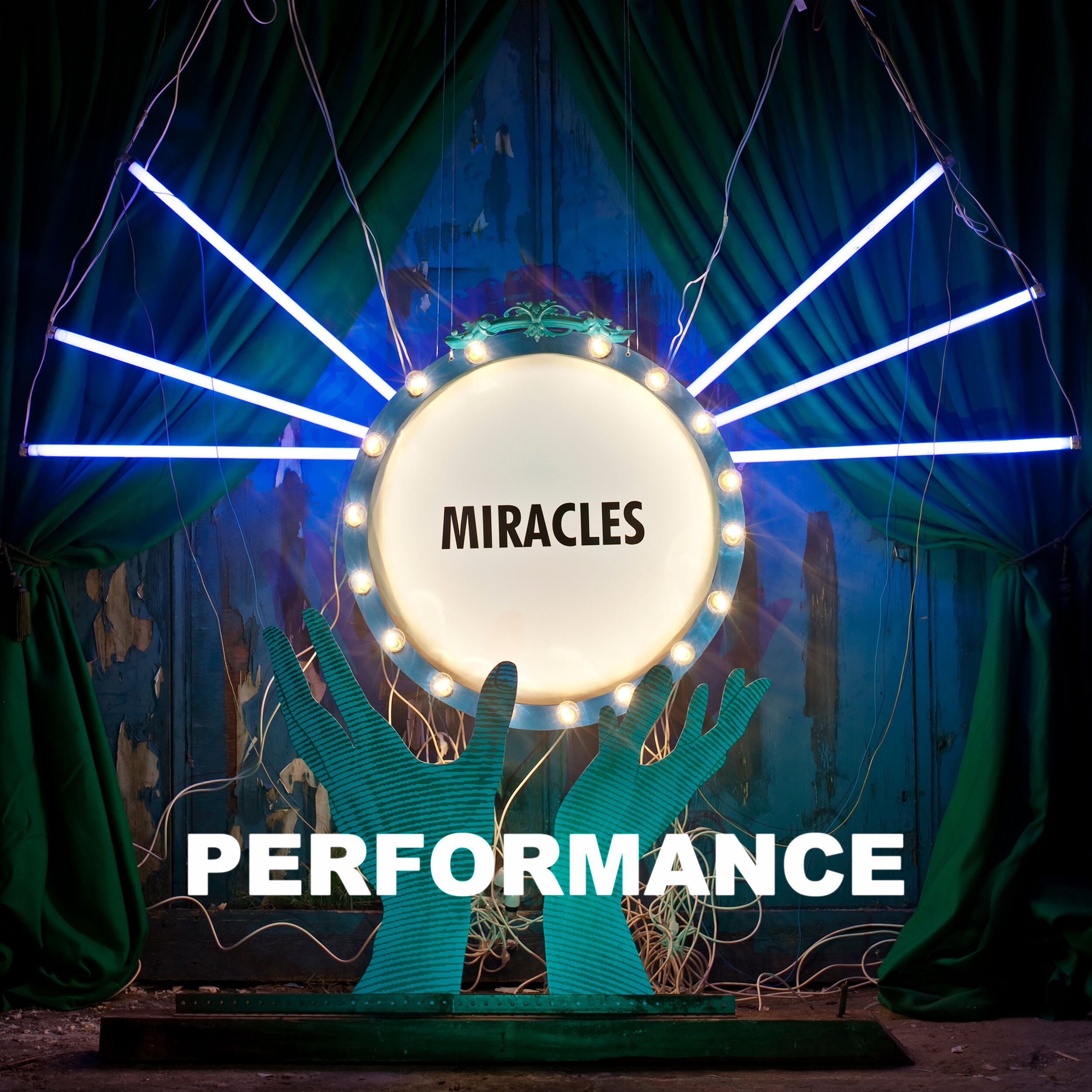 The image shows a theatrical stage with a large digital screen that displays the word 'MIRACLES' inside a circle surrounded by lights, with the word 'PERFORMANCE' overlayed at the bottom. There are green drapes on the sides, and blue and purple light