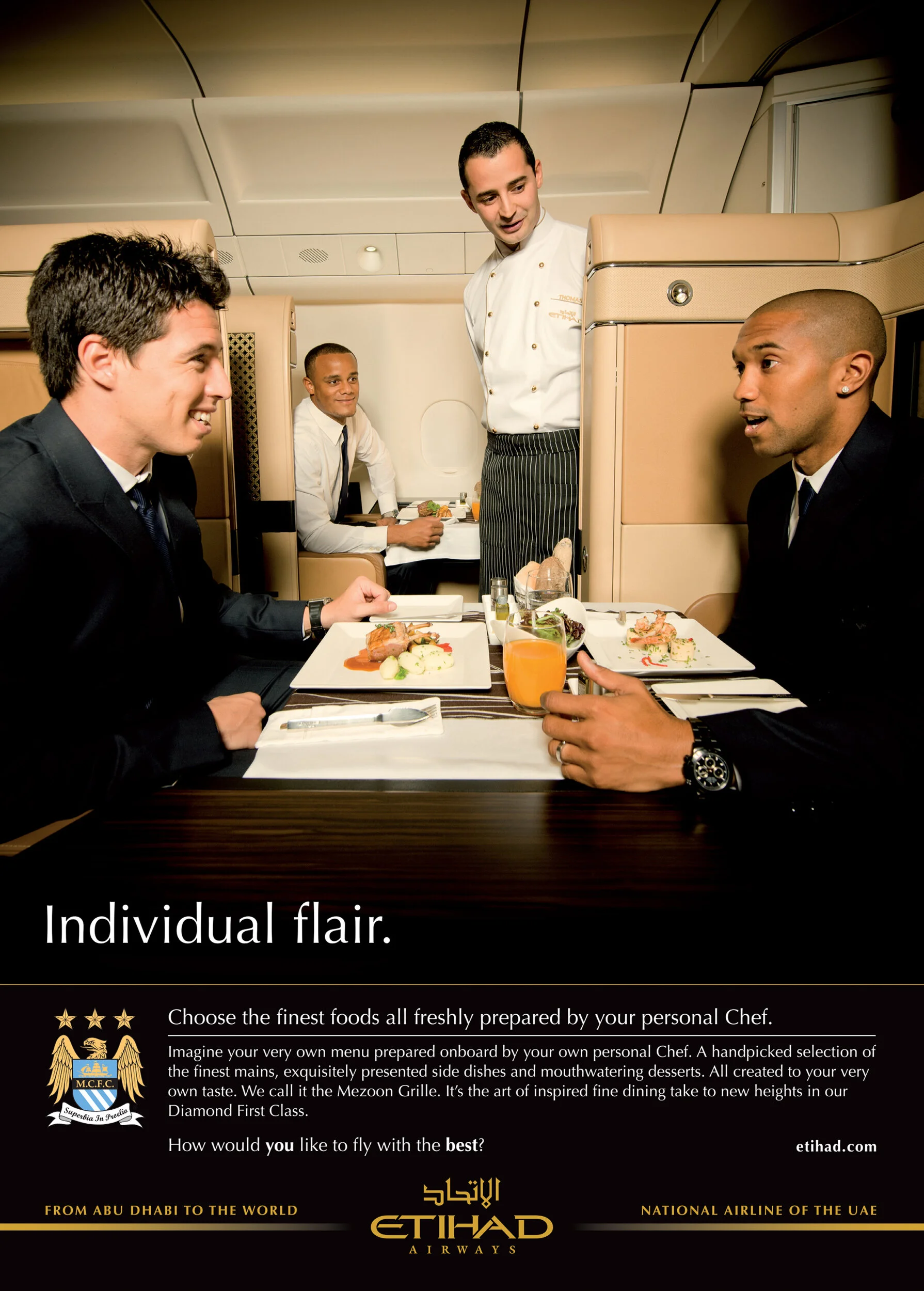 Four men dining on an airplane, with a chef standing in front of two of them, and a man sitting in the background. The men are dressed in formal attire, and the table has plated gourmet food and drinks.