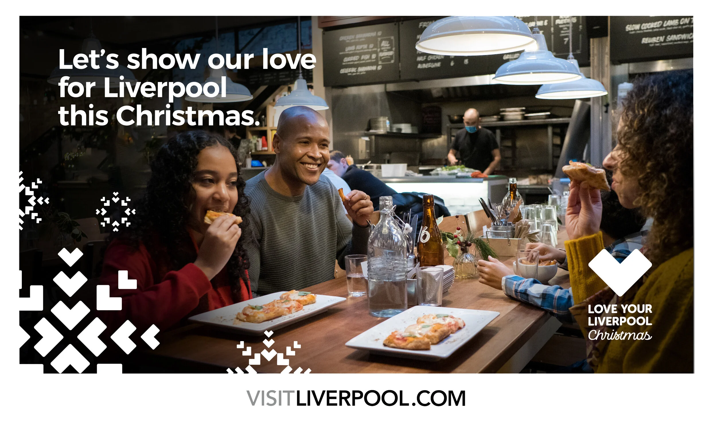 Group of people enjoying pizza at a restaurant celebrating Christmas with a festive message about loving Liverpool this Christmas.