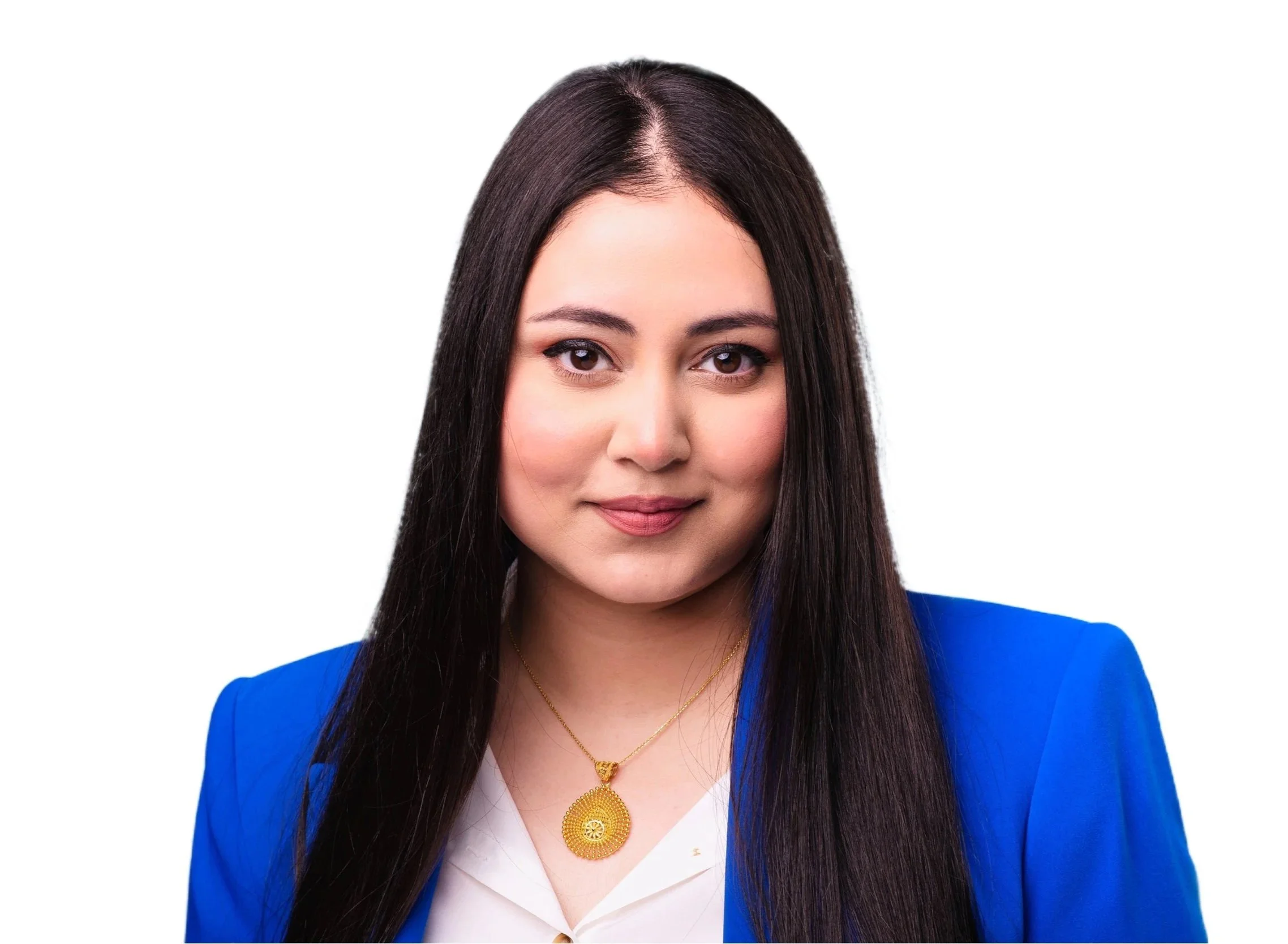 A woman with long dark hair, wearing a blue blazer and a gold necklace with a large pendant, smiling softly against a white background.