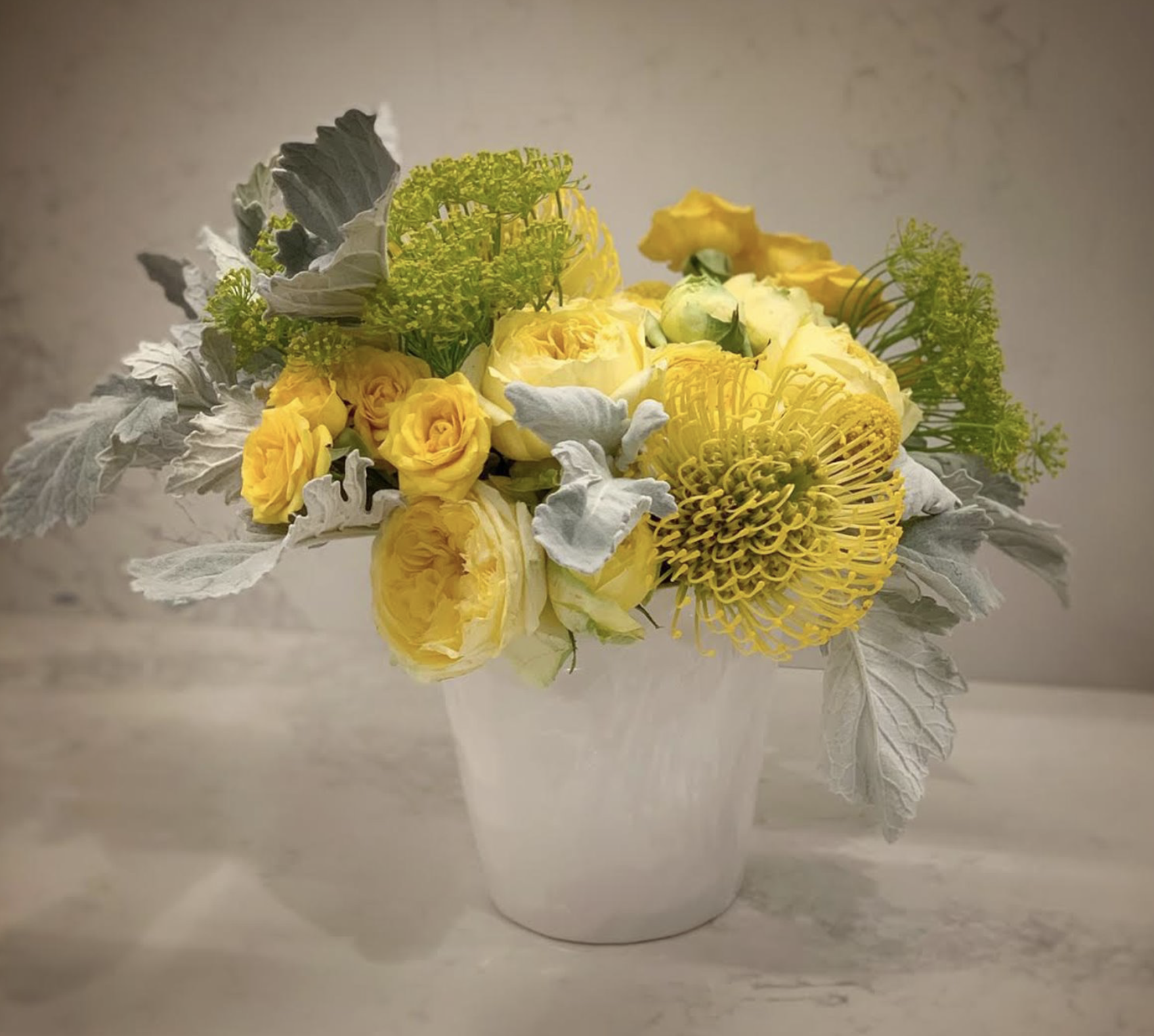 Yellow Yarrow, Queen Anne’s Lace, Dusty Miller, Spray Rose, Delano Ranunculus, Garden Rose, and Pincushion Protea
