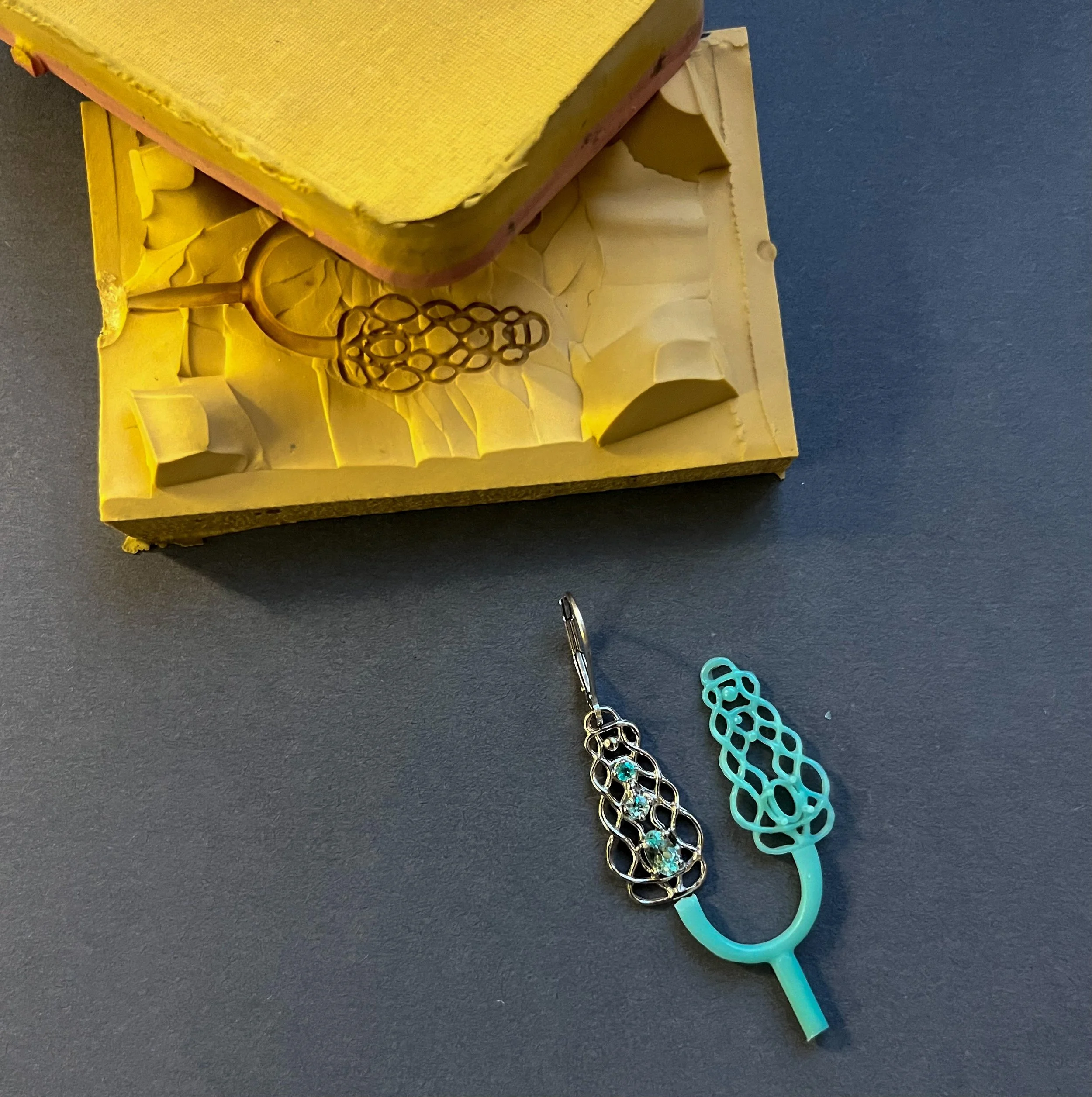 Jewelry mold and earring with a blue wax cast on a dark background