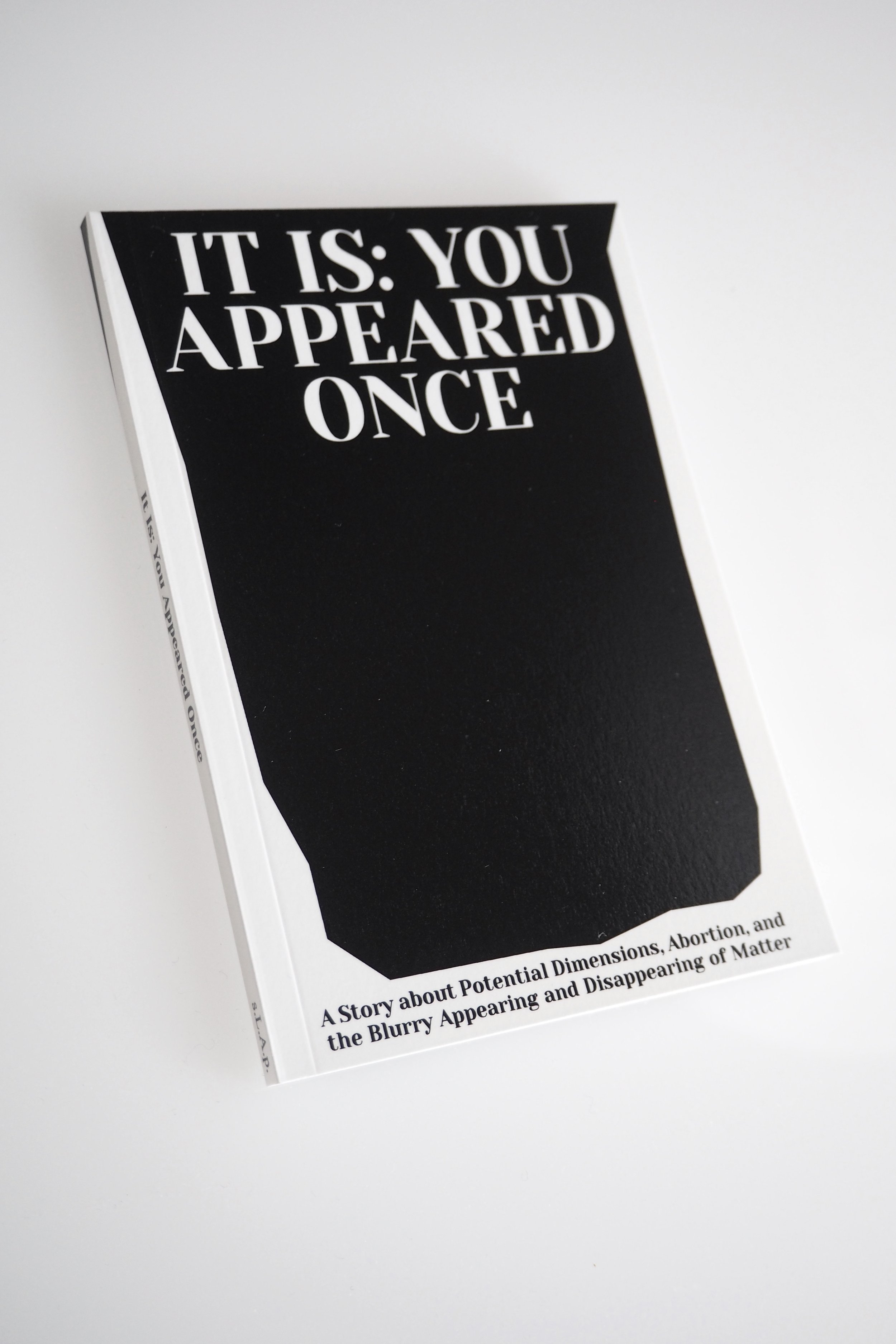 A photo of a book Cover reading "It is: You Appeared Once" in white on black background. At the bottom a white stripe that extends up to the top along the edges, with the subtitle of the book.